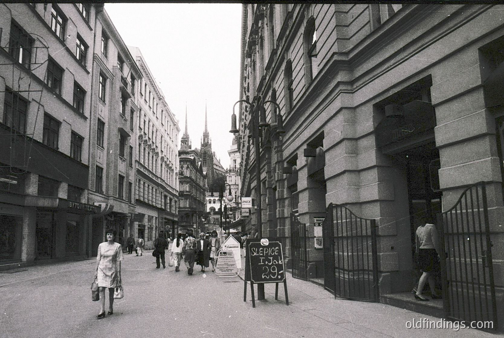 Where is this: narrow urban street flanked by mid-rise Soviet-era buildings, likely Eastern Europe