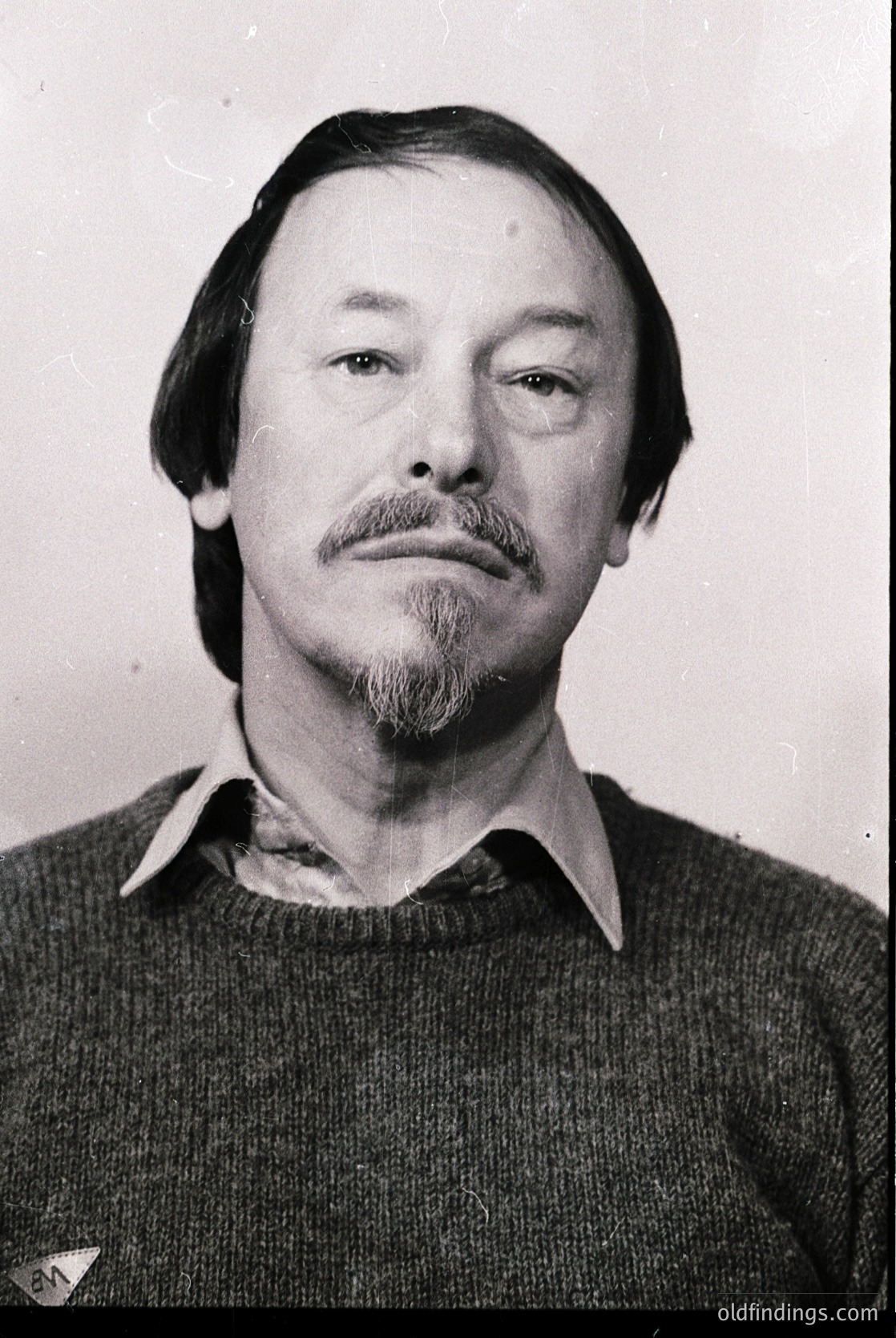 Portrait of a man with a mustache and beard, wearing a collared sweater. Mid-century styling suggests or . Neutral expression, plain background.