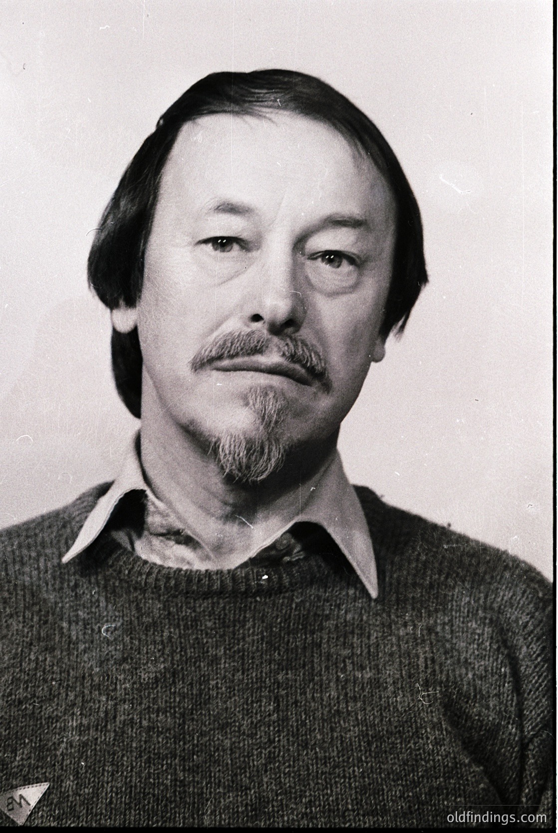 Portrait of a man with a mustache and beard, wearing a collared sweater. Studio lighting suggests a formal or official setting, likely from the mid-20th century (1950s–1970s). His direct gaze and neutral expression indicate a possible identification or documentation photo.