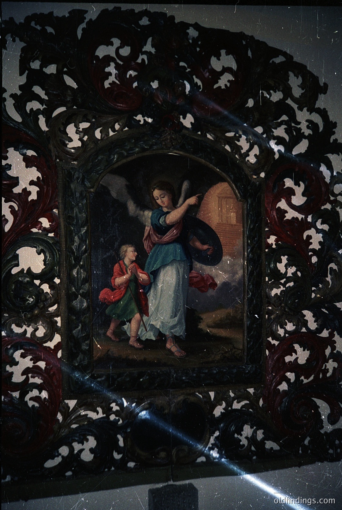 Baroque-style religious painting framed in ornate damask pattern, depicting an angelic figure (blue robe, wings) presenting a child (red garment) to a dark-haired figure in a niche. Likely 17th–18th century European religious art, possibly Italian or Spanish. Ideal for historical research, art history, or religious iconography studies.