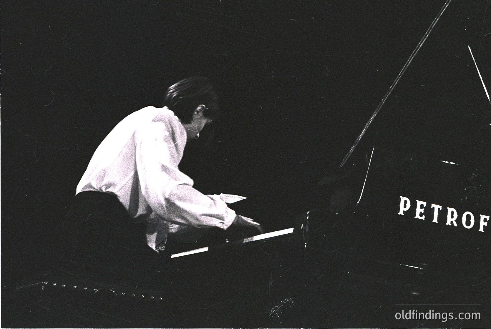 Black-and-white concert shot of pianist performing at the **Petrof** venue, likely **Petrofka Hall** (St. Petersburg, Russia). Stage lighting highlights the pianist in a focused, mid-performance pose. Mid-20th century concert hall interior visible. Ideal for historical music research or vintage concert imagery.