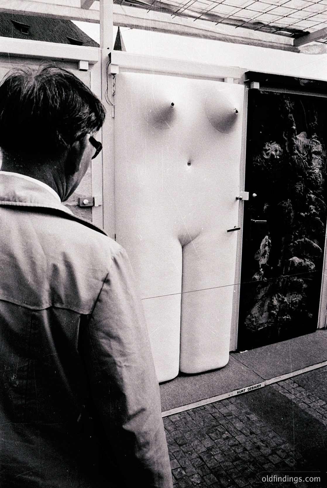 Mid-century industrial refrigerator with vintage design—curved door panels and riveted metal frame—packed with bundled fish. Man in glasses and light jacket examines contents, suggesting a market or processing facility. Likely 1950s–1960s, possibly coastal or fishing port.