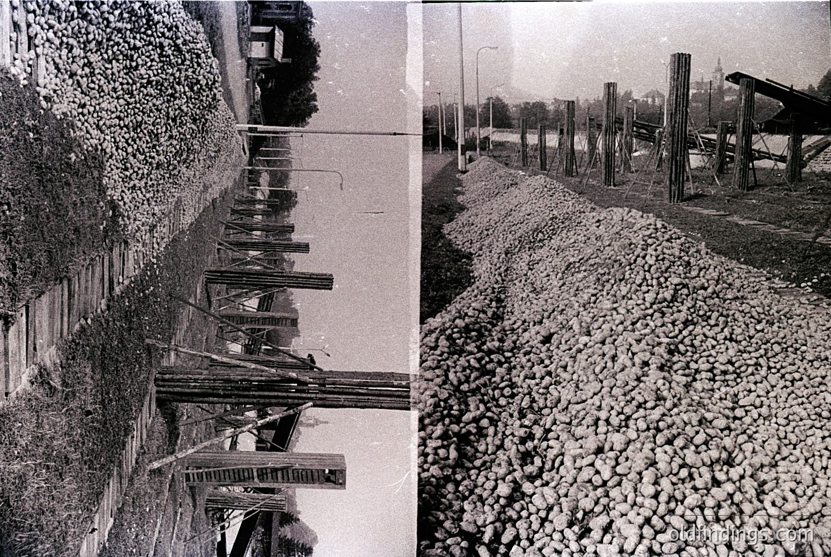Diatribe of rusted, weathered railway tracks flanked by gravel piles, likely mid-20th century industrial setting. Abandoned wooden supports and overgrown vegetation suggest disuse.