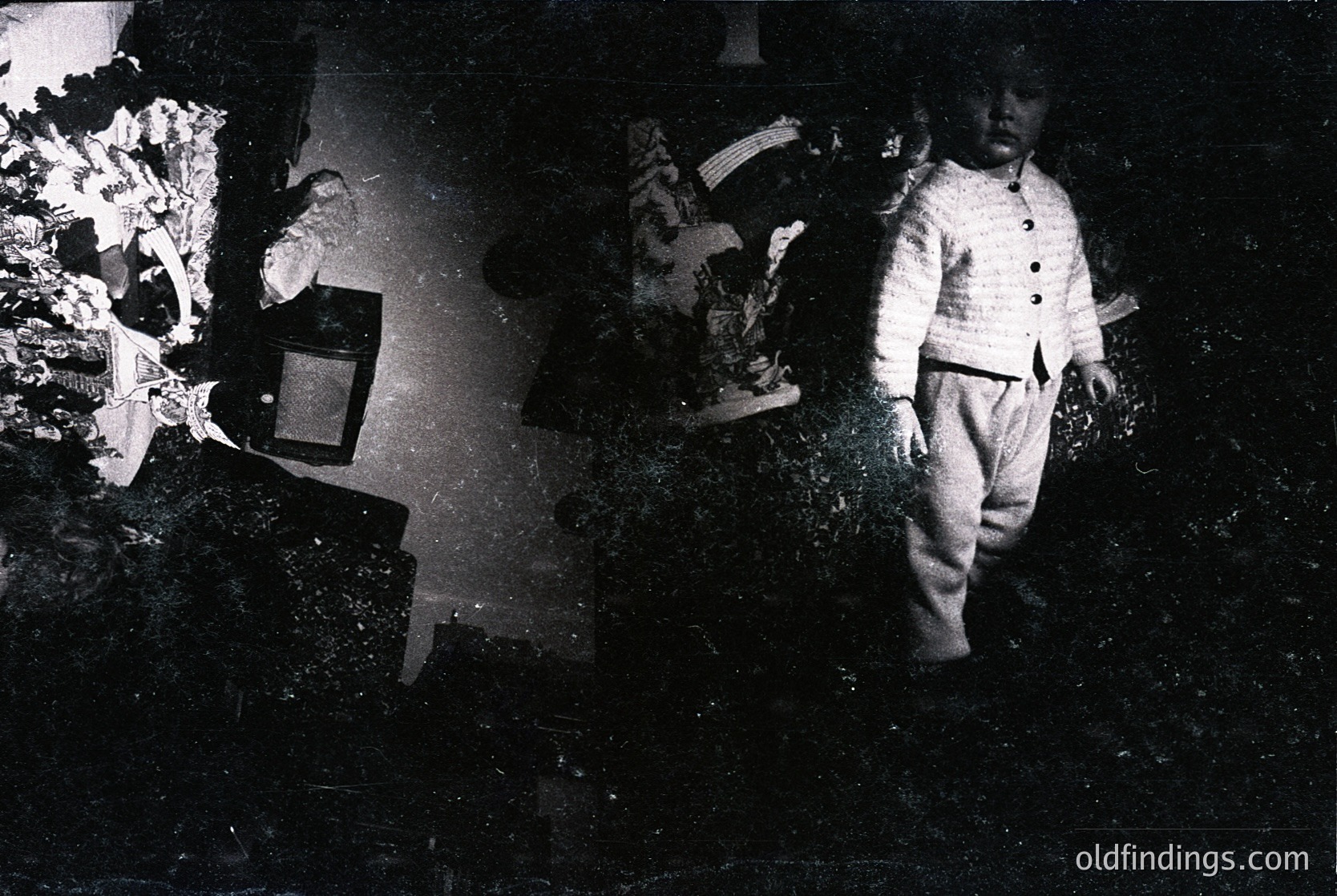 Vintage split-image portrait of two children in early 20th-century attire, one seated at a wooden table with a typewriter, the other standing in a garden. Darkroom-style contrast highlights textures—knit sweater, floral wallpaper, and overgrown foliage. Likely mid-1900s, Western Europe/USA.