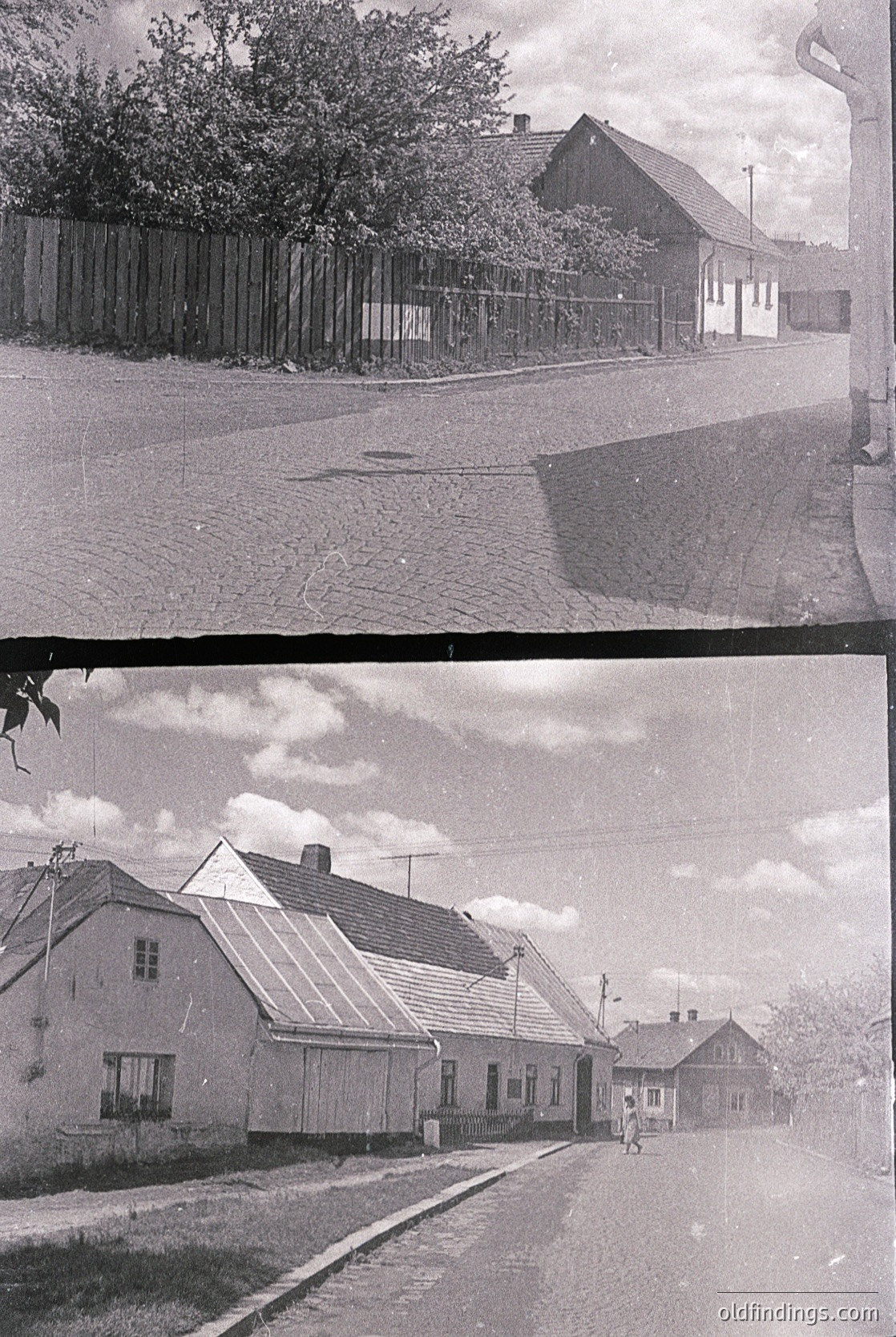 Vintage black-and-white street scene featuring modest Soviet-era brick houses with gable roofs and simple window designs. Cobblestone road with a lone pedestrian in the lower shot, surrounded by overgrown greenery and utility poles. Likely Eastern European, mid-20th century.