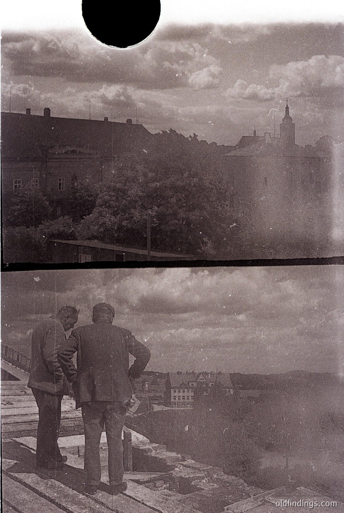 Two men in mid-20th-century suits stand on a rooftop overlooking a European cityscape, likely . Architectural details include a prominent church spire and low-rise buildings. The composition suggests urban planning and post-war reconstruction.