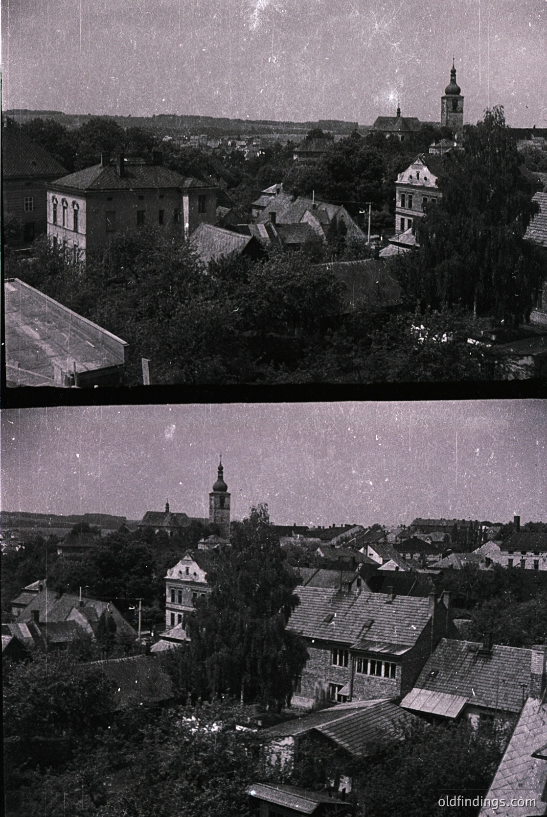 Vintage aerial view of a European village with dense, low-slung wooden architecture and a prominent church steeple. The roofs are steeply pitched with slate or tile, surrounded by lush greenery. Likely Eastern European, mid-20th century.
