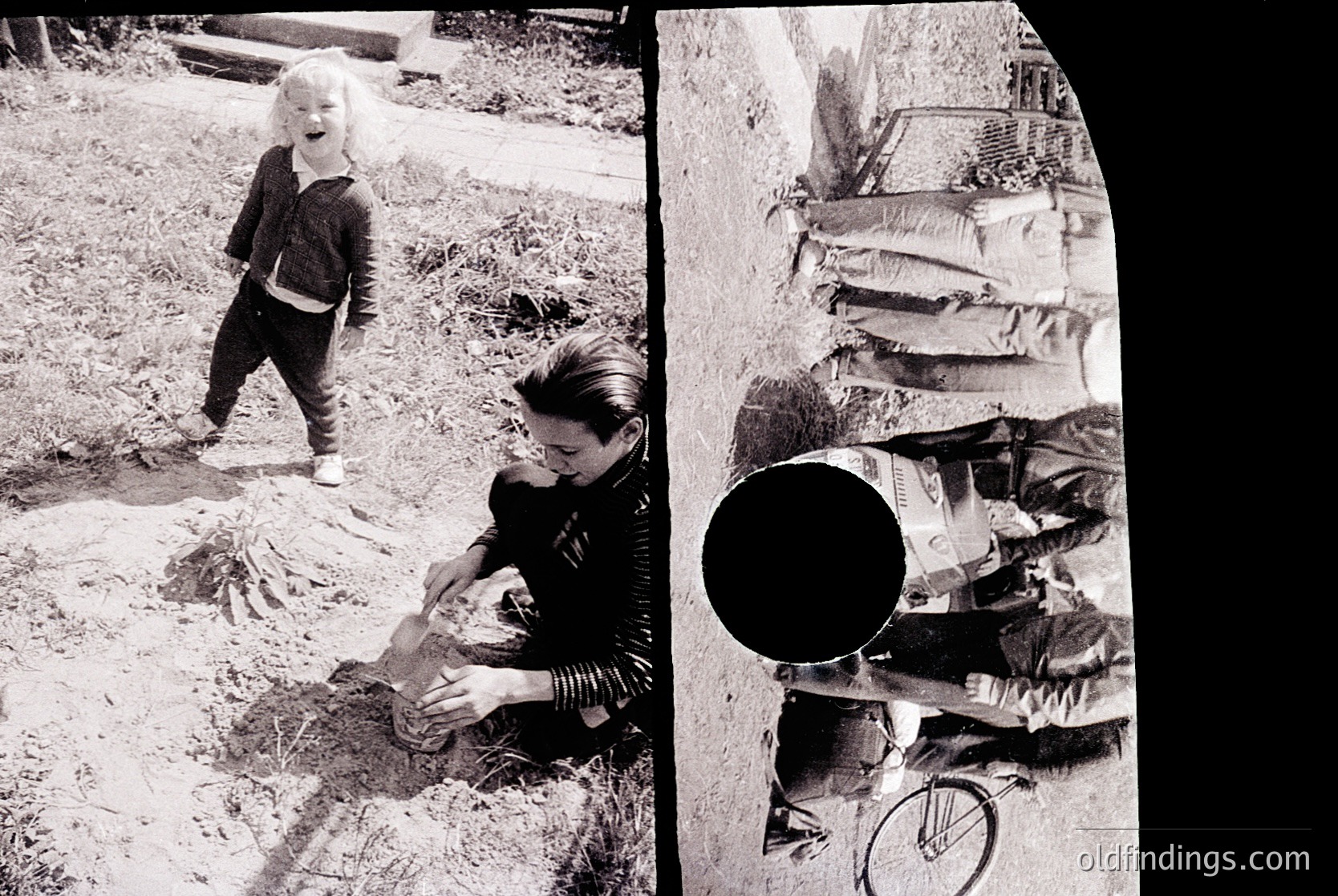 A candid 1970s-era black-and-white photo of a woman kneeling in a garden, tending to a small child standing beside her. The woman wears layered clothing and a headscarf, while the child stands in rolled-up pants. A vintage camera lens (right side) and a blurred urban wall with graffiti symbols () frame the scene. Likely European domestic life.