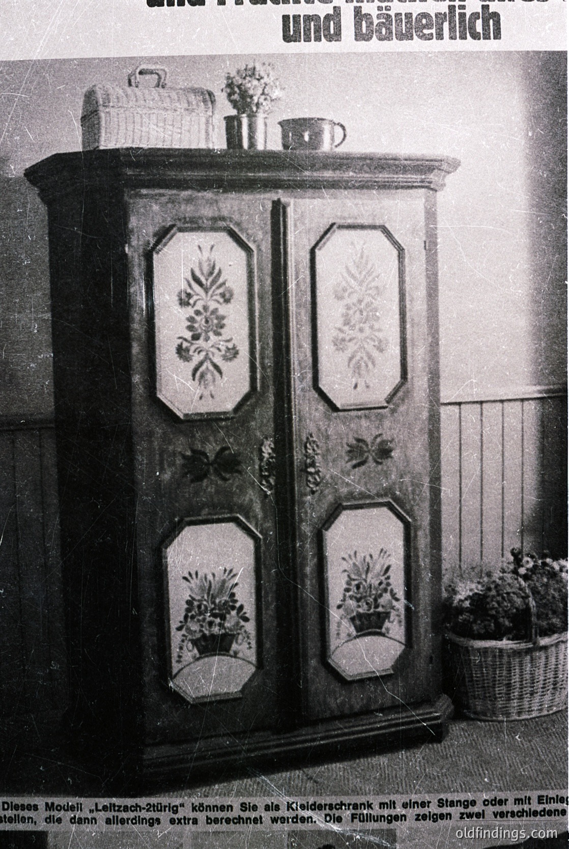 Vintage German cabinet from the 1960s–70s, showcasing floral embroidered panels in geometric frames. Features dual doors with decorative motifs, a woven basket atop, and a teacup on the shelf. Text suggests "Leitzach-2tür" model for clothing storage. Ideal for mid-century interior design or historical research.