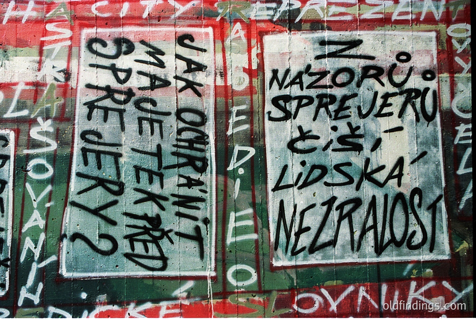 Graffiti-covered wall featuring bold, black text in Czech: *"Jak poznat spravedlnost?"* (left) and *"Nazoru spřeru či lidská nezralost"* (right). Peeling paint reveals faded red and white underlayers. Likely from **Czech Republic**, 1980s–1990s era.