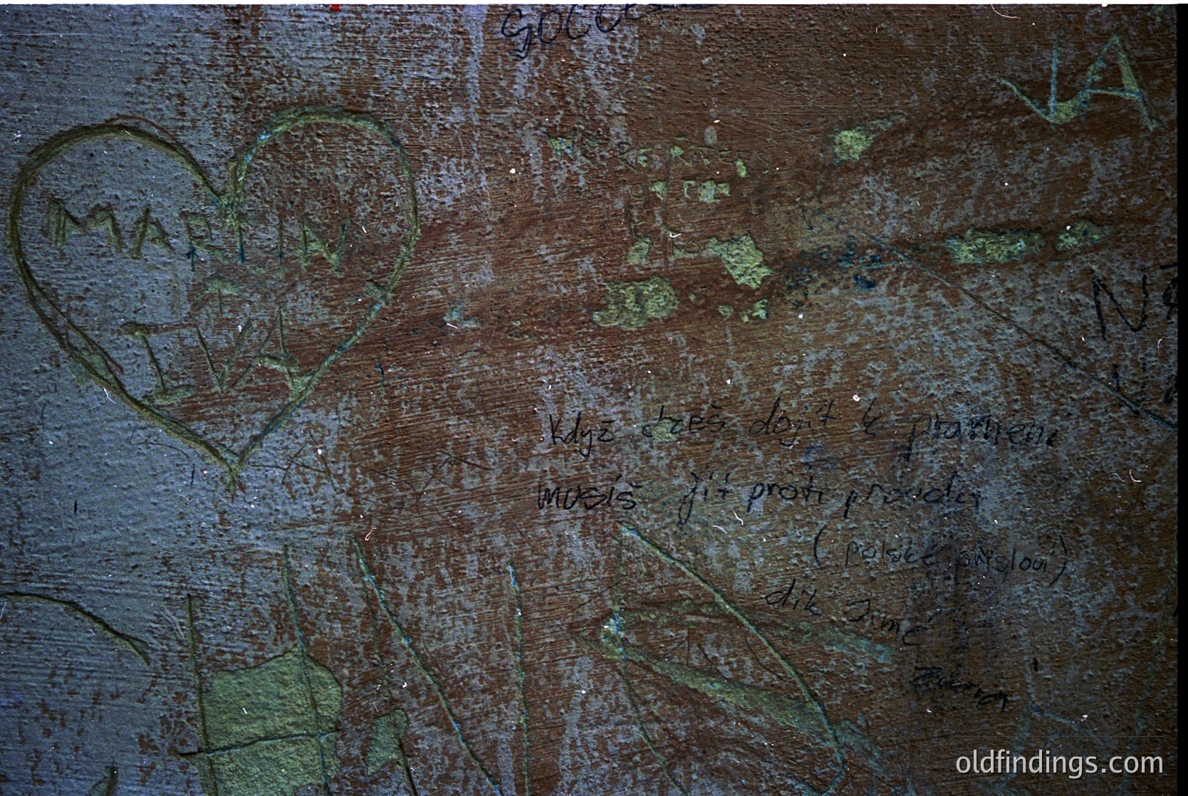 Graffiti etched into weathered concrete wall: heart shape, partial text *"My love..."* and *"forever"* with faded signatures. Surface shows moss growth and cracks. Likely urban or abandoned structure.