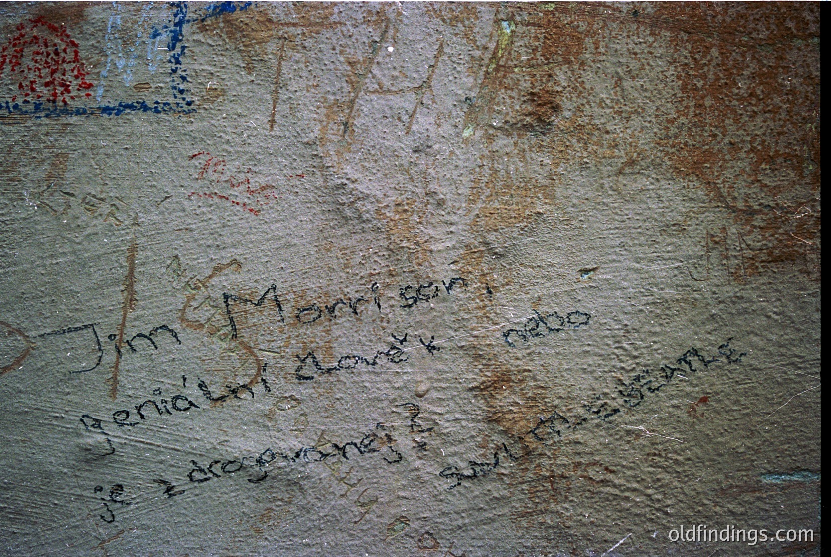 Graffiti etched into weathered stone wall, featuring faded inscriptions in Cyrillic script. Visible text includes "Jim Morrison" and "1970" among other illegible markings. Likely part of a historic or cultural site.
