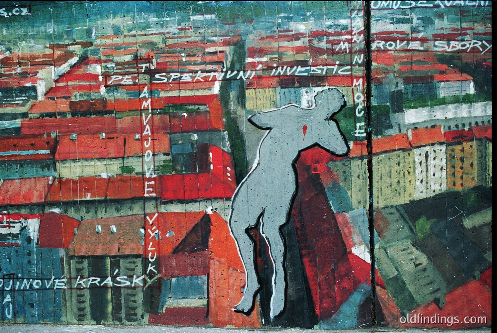 Vibrant mural-style artwork depicting a lone figure in mid-jump against a chaotic urban backdrop of red-brick buildings and text fragments in Czech. Bold, expressive brushwork and striking red/orange hues dominate. Likely from **Czech Republic**, **1960s–1980s** avant-garde or socialist-era art.