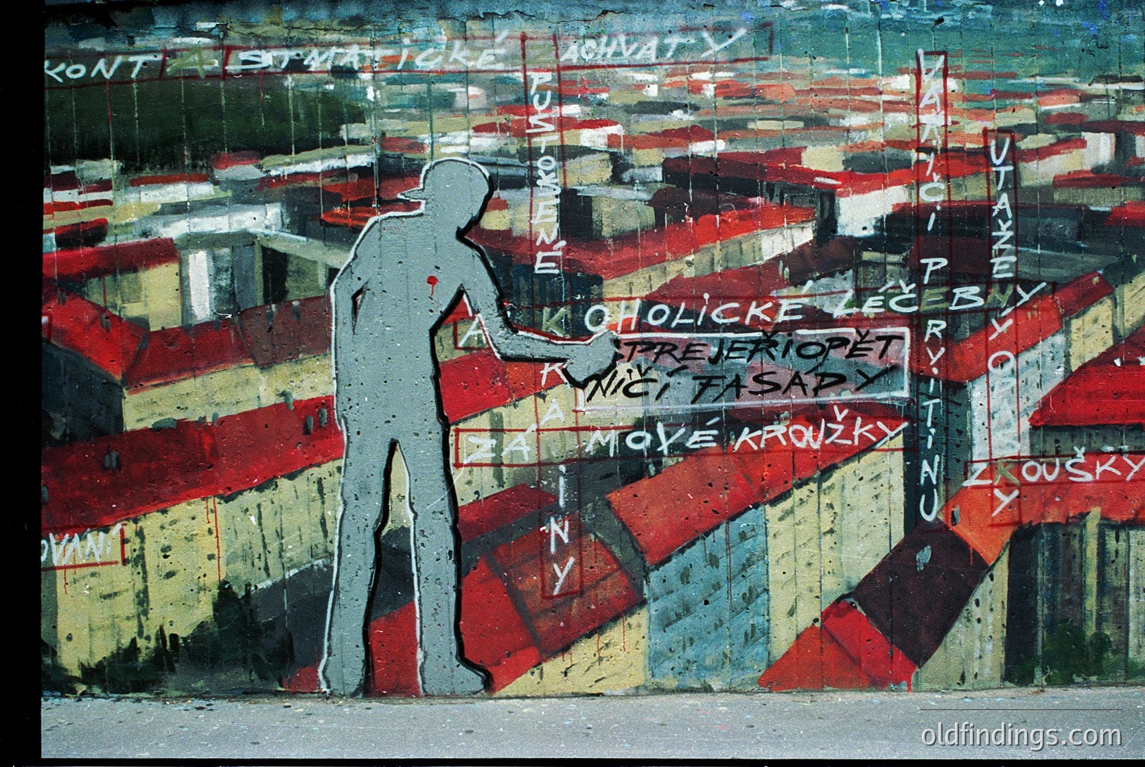 Vibrant mural depicting a silhouetted figure climbing a striped wall with Cyrillic graffiti text in red, white, and blue. Urban art style with layered, weathered paint. Likely Eastern European, – era.