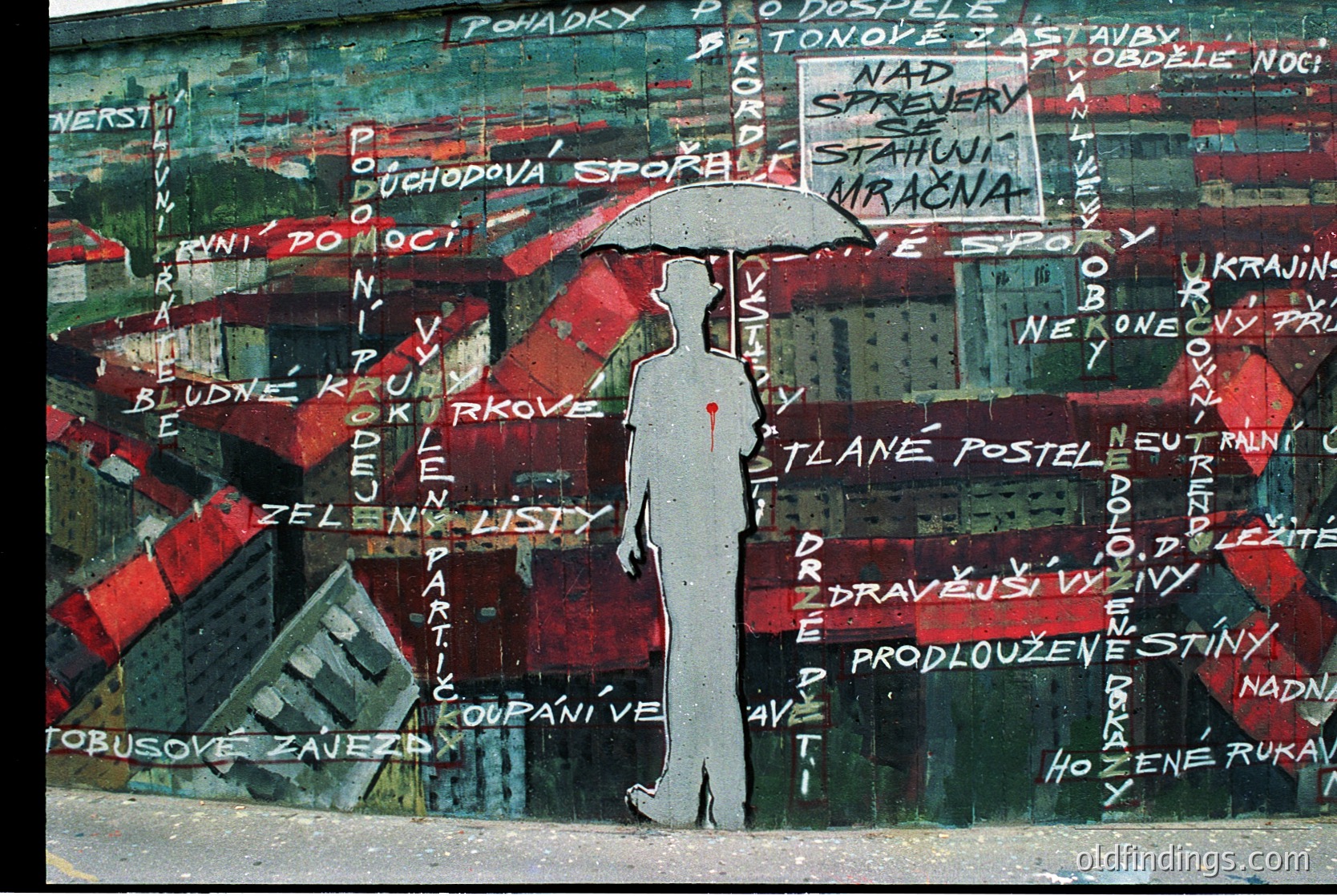 Street mural featuring a silhouetted figure holding a red umbrella against a backdrop of fragmented Czech/Czech-inspired text and geometric shapes. Likely from Prague’s urban art scene, 1980s–1990s era. Evokes Cold War-era dissent or poetic rebellion.