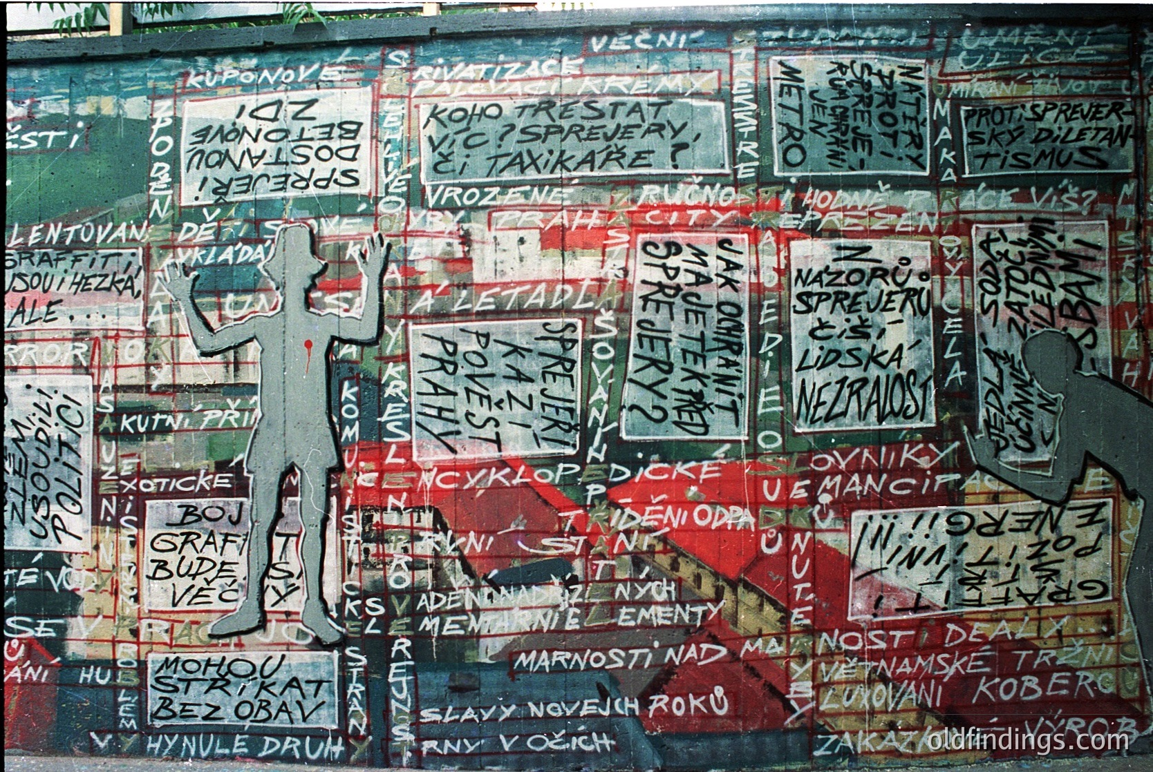 Vibrant graffiti mural featuring bold, layered Cyrillic text in red, black, and white on a weathered wall. Central figure appears to be a stylized human silhouette in red. Likely from **Czechoslovakia** or **East Bloc** era (1960s–1980s), reflecting political/social commentary. Text includes phrases like *"svoboda"* (freedom) and *"komunistický"* (communist).