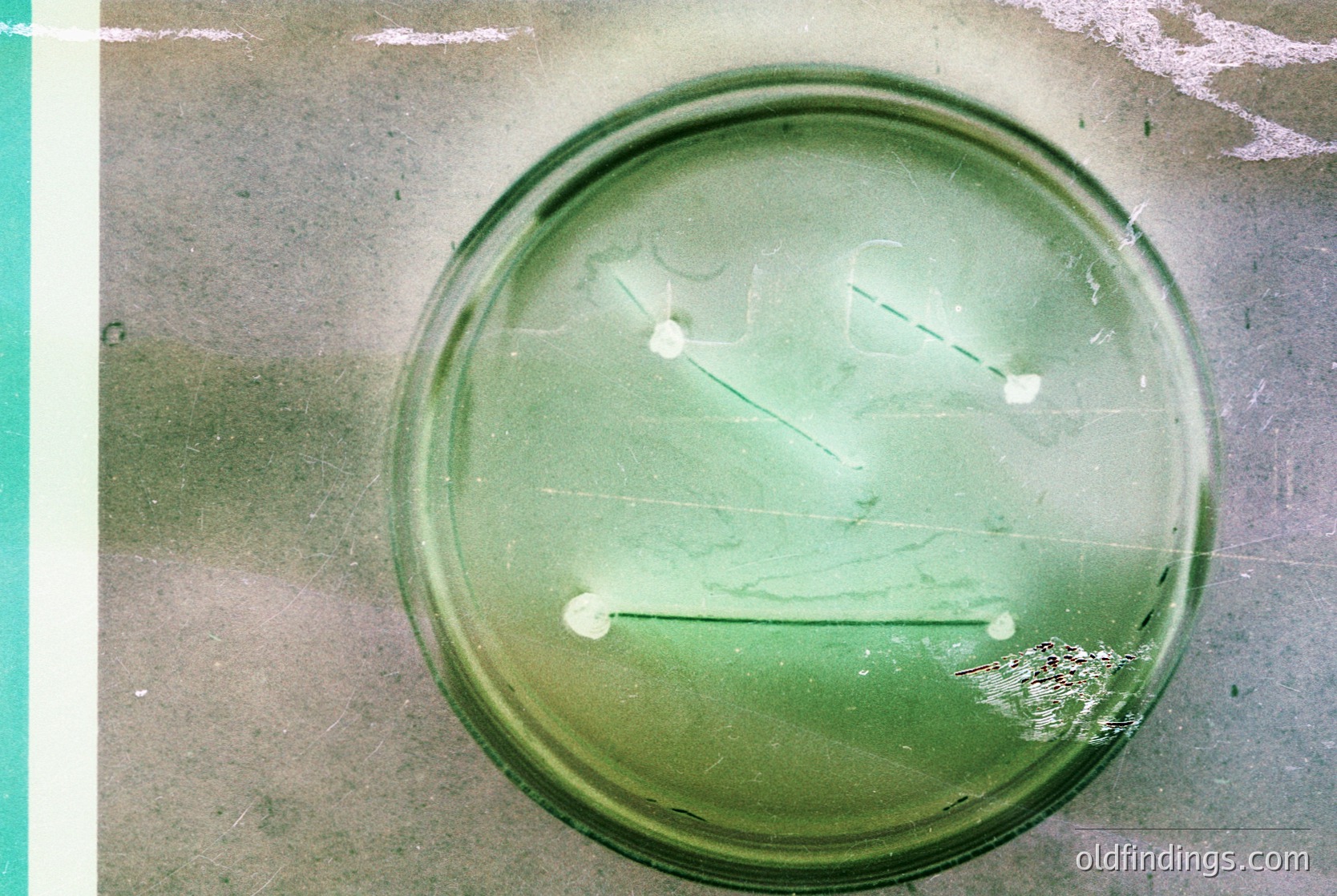 Vintage green glass ashtray with cracked enamel, resting on a worn concrete surface. Distressed texture suggests mid-20th century industrial design. Ideal for retro decor, vintage collections, or historical research.