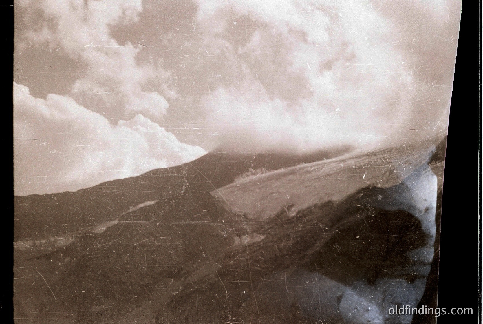 Vintage sepia-toned aerial view of a snow-covered mountainous landscape with a winding road cutting through terrain. Evidence of early 20th-century photography techniques. --- *Note: Without clearer landmarks or context, precise location/time remains speculative. The sepia tone and composition suggest historical stock or archival value.*