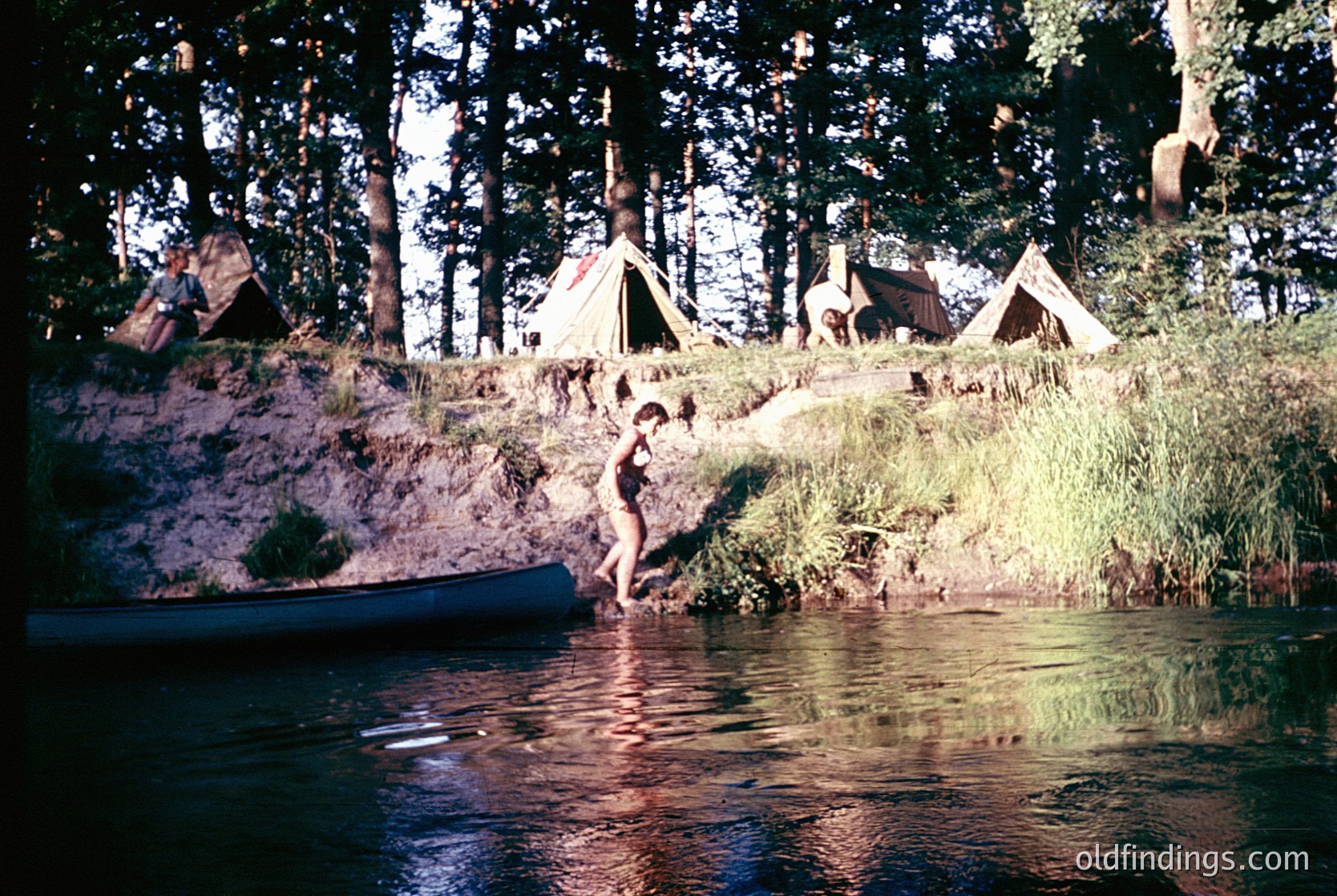 Vintage camping scene by a serene lake, featuring a woman in a swimsuit stepping from a canoe into shallow water. Wooden canoe and forest tents in background suggest mid-20th century outdoor recreation. Warm sepia tones enhance nostalgic atmosphere.