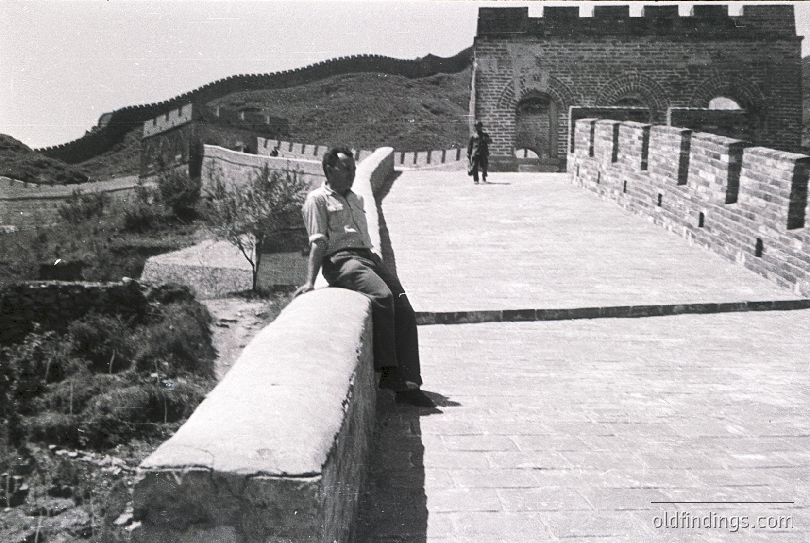 Man poses on Great Wall parapet, 1960s–70s China. Iconic brick fortification with watchtowers and wide walkway. Mid-century travel or historical documentation.