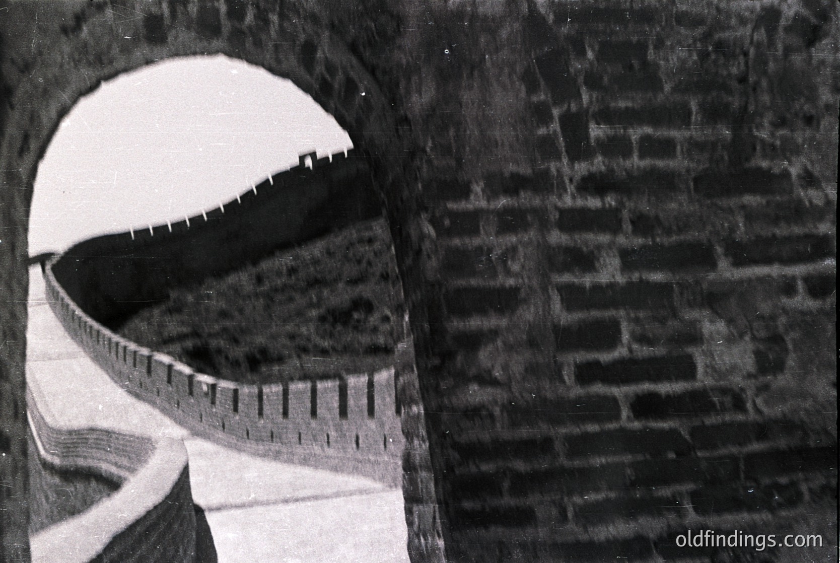 Close-up of a vintage measuring tape wrapped around a brick archway, showcasing its scale markings. The brickwork suggests industrial or historical architecture, likely mid-20th century.