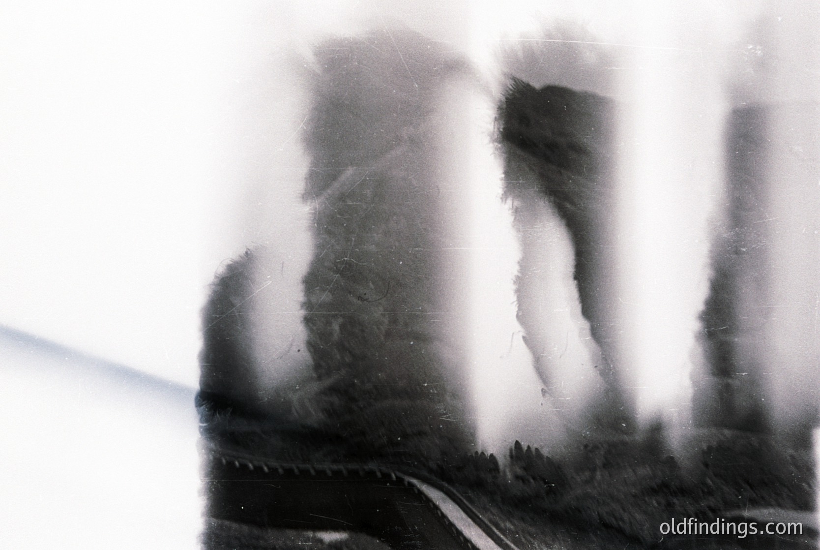 Vintage monochrome photo of blurred industrial pipes and machinery, likely from a factory or power plant. Distinctive riveted metalwork and steam vents suggest mid-20th century engineering.