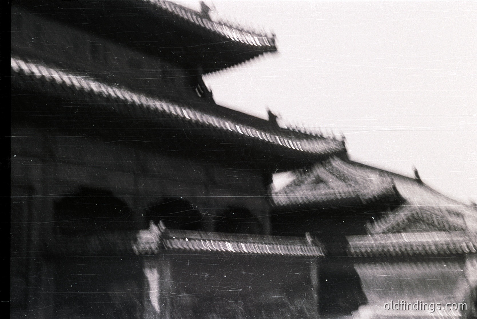 Vintage black-and-white shot of traditional East Asian pagoda-style architecture with tiered, curved eaves and ornate brackets. Blurred motion suggests dynamic movement or handheld camera. Likely –1980s due to grain and style. Ideal for or research.