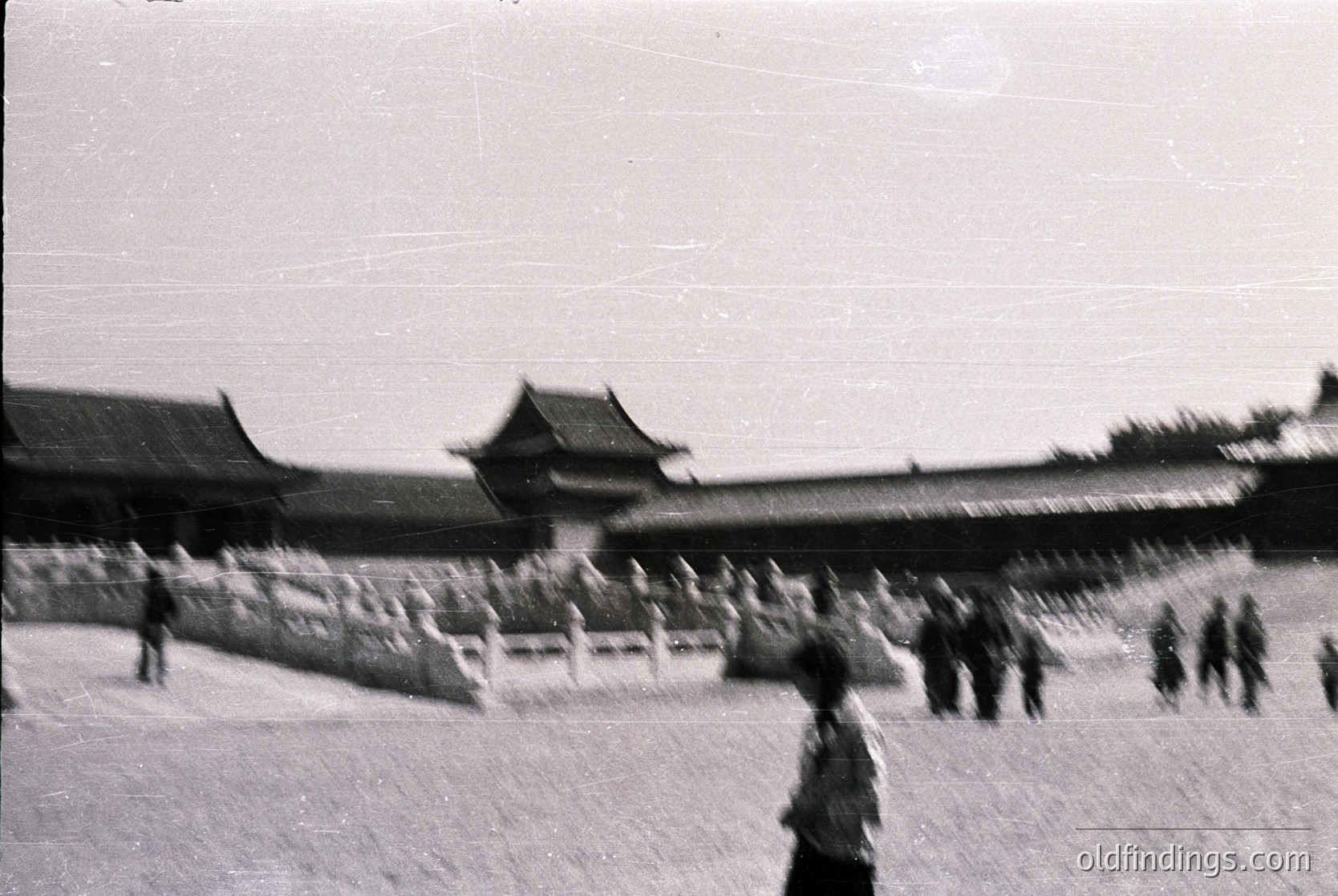Vintage black-and-white photo of traditional East Asian palace architecture with upturned eaves and tiled roofs, likely or -inspired. Crowds of blurred figures suggest mid-20th century () public gathering or tour. Stone walls and white picket fence add historical authenticity for design references.