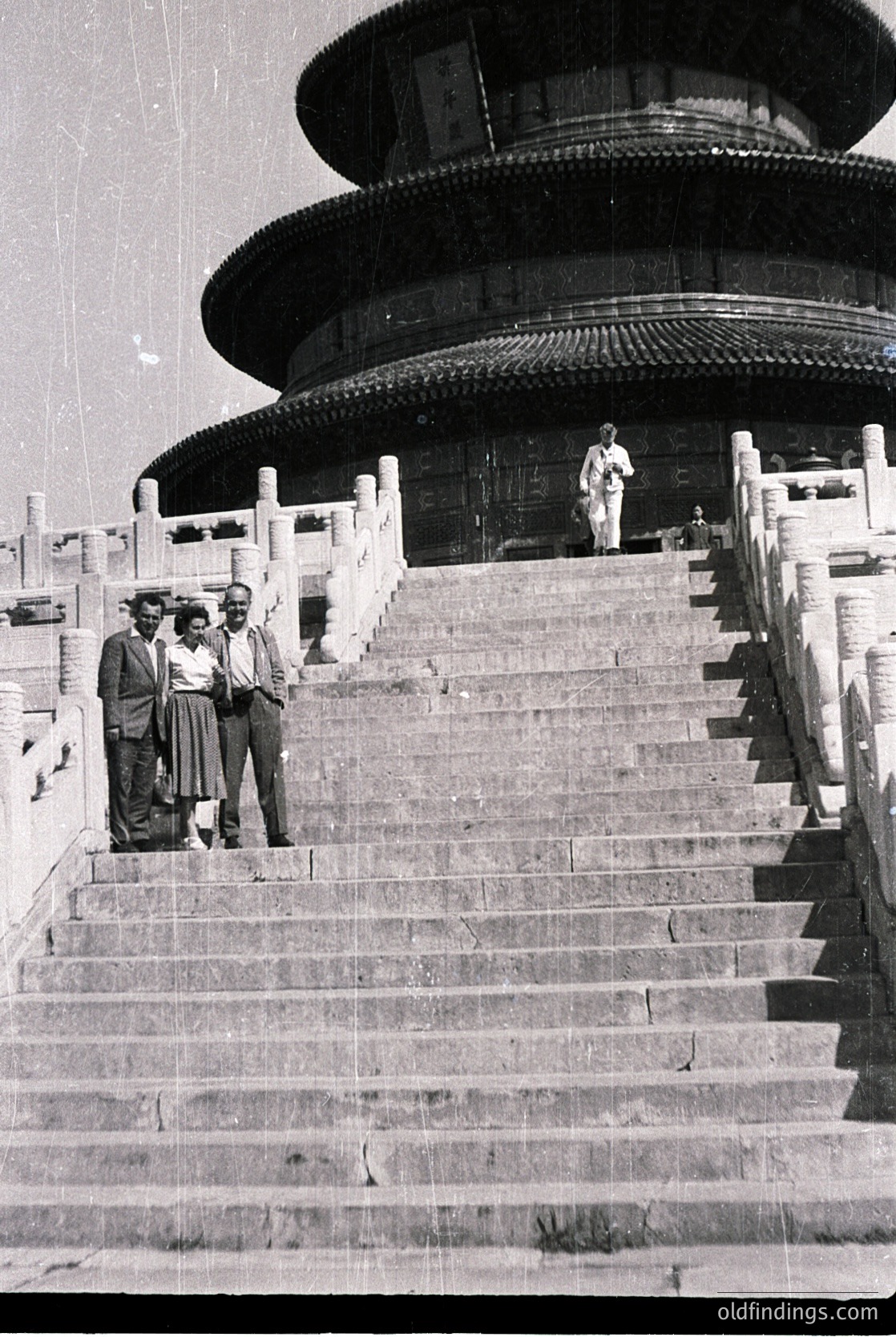 Three men pose on wide stone steps leading to the multi-tiered Hall of Prayer for Good Harvests, Temple of Heaven, Beijing. Mid-20th century attire suggests 1950s–1960s era. Iconic Ming/Qing dynasty architecture with circular, tiered roof.