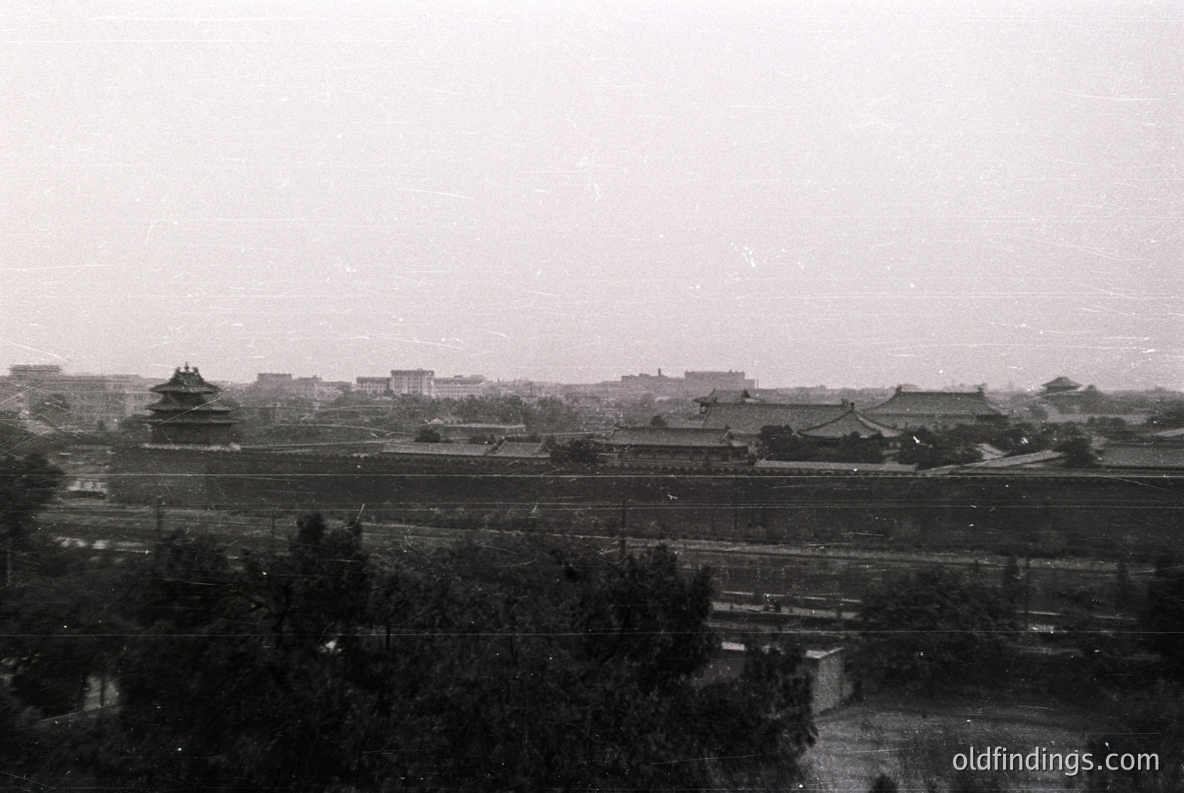 Black-and-white aerial view of the Forbidden City’s northern walls and rooftops, Beijing, China. Traditional Chinese architecture with tiled roofs and watchtowers visible. Likely mid-20th century due to monochrome and urban layout.