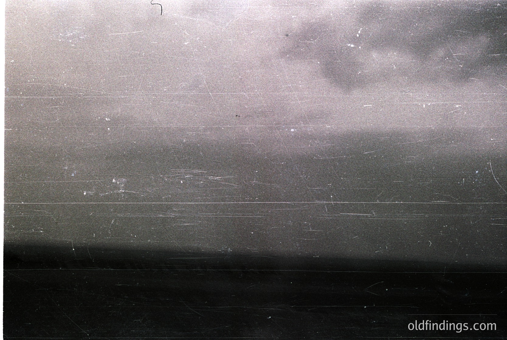 Vintage black-and-white photo of a train window showing blurred motion and light reflections. Horizontal scratches and slight fogging suggest age and wear. Likely mid-20th century travel documentation.