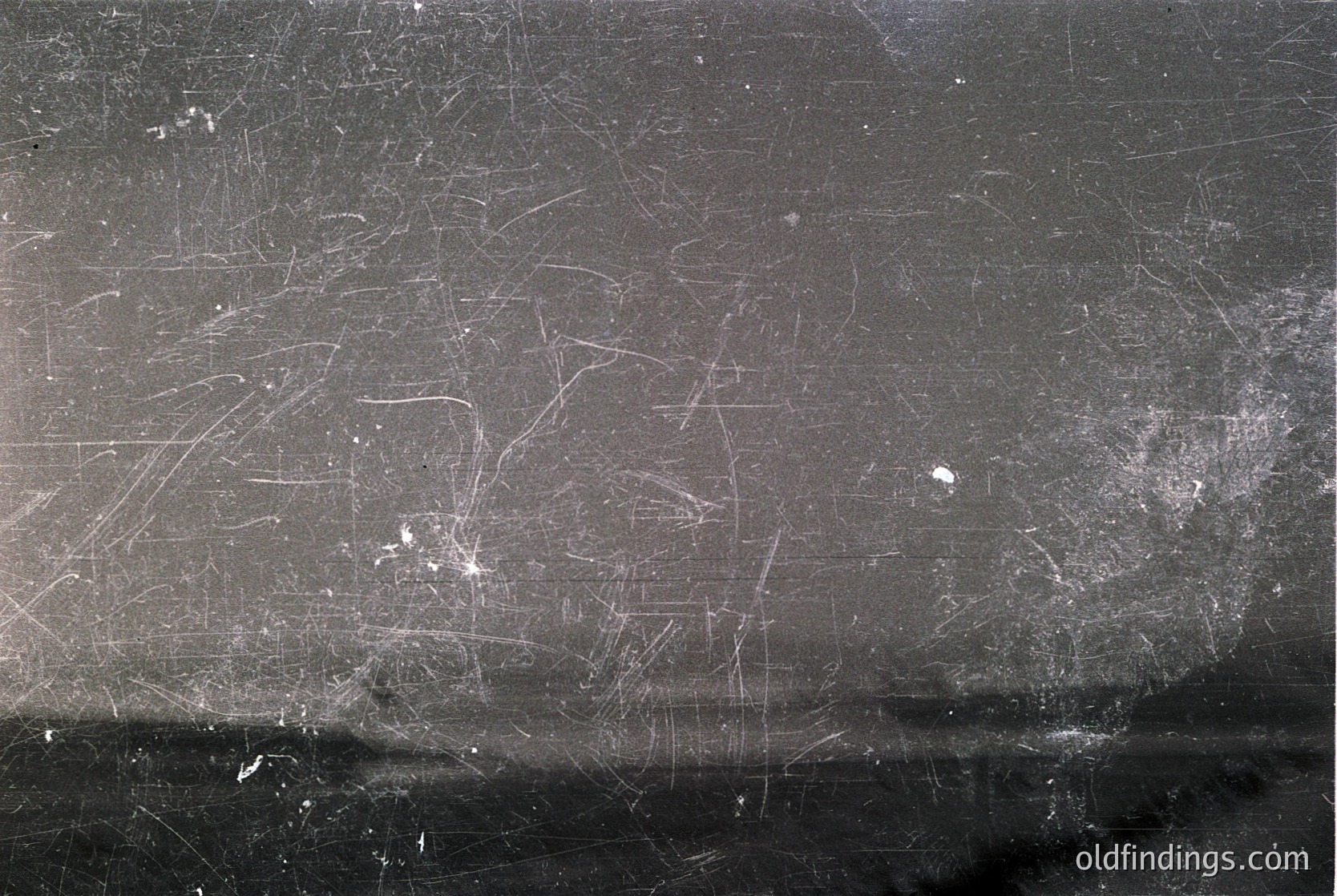 Close-up of weathered, scratched metal surface with faint graffiti-like markings. Likely industrial or urban setting, suggesting aged infrastructure. Texture highlights corrosion and wear over time.