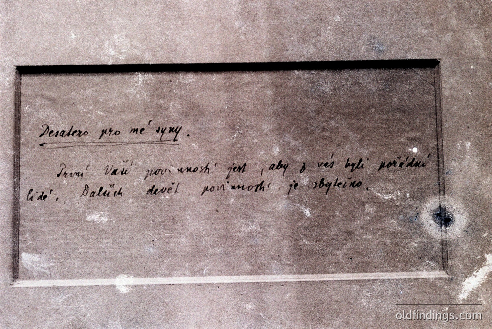 Vintage handwritten inscription on aged stone plaque in Cyrillic script, likely Bulgarian. Text reads: *"Десатеро про ме сигури. Дрви Ваш по-мощни жест и аби д вес быха породени тидо. Далуч девет по-мощни же сбоглеино."* Framed by black metal border, showing signs of weathering and wear. Potential historical or cultural artifact from Bulgaria.