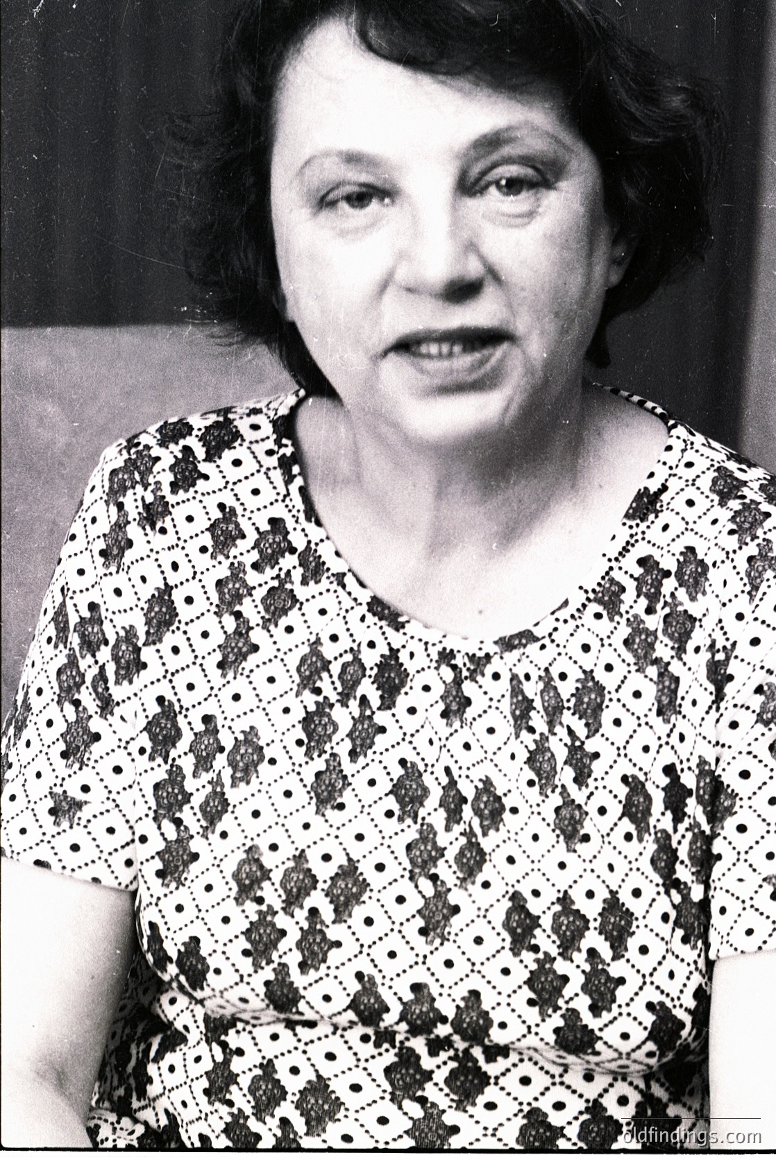 Portrait of an individual in a patterned blouse with geometric and floral motifs, likely mid-20th century. Soft focus and black-and-white style suggests vintage photography. Expression conveys thoughtful intensity.