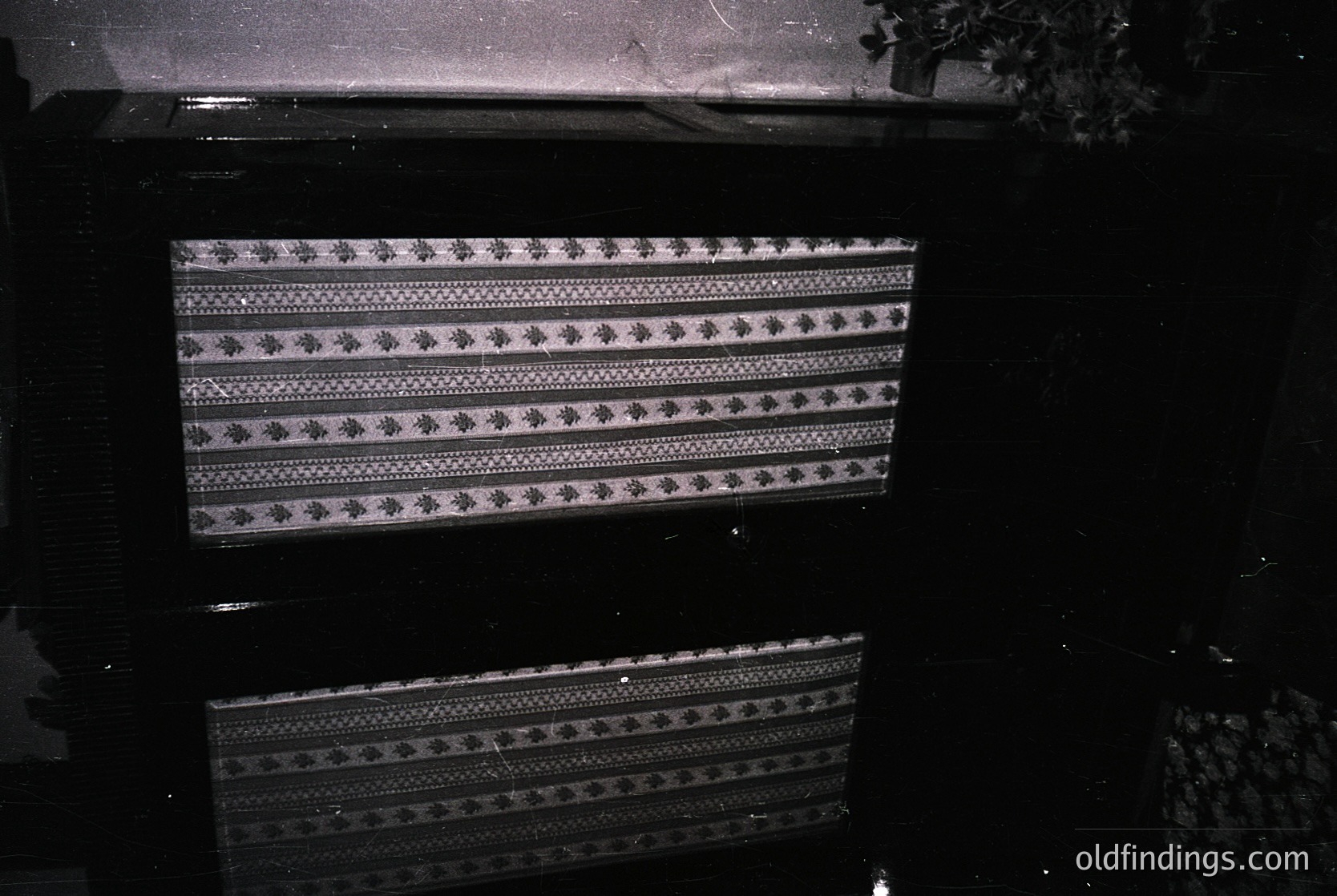 Vintage woven textile with geometric diamond and zigzag patterns, likely a traditional rug or tapestry. Dark, moody lighting enhances texture and depth. Possible Central Asian or Middle Eastern craftsmanship, indicative of 20th-century handwoven artistry.