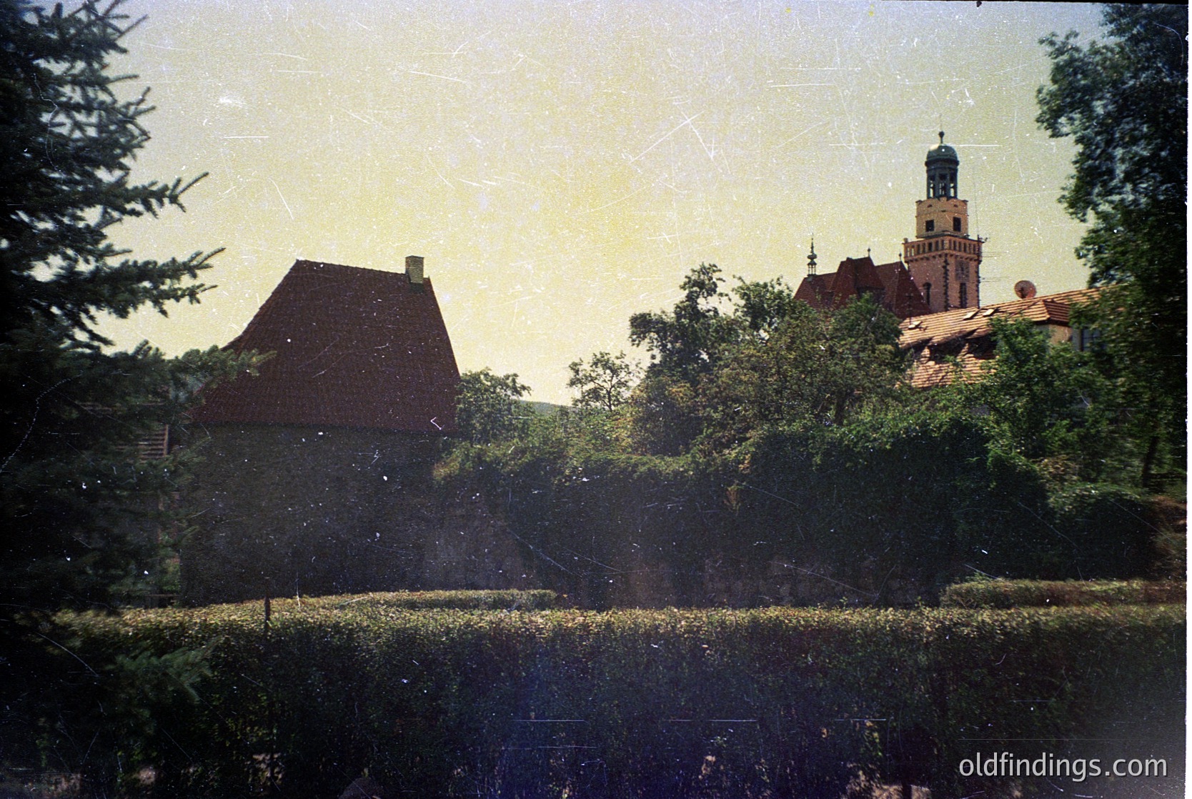 Vintage sepia-toned photo of a European castle tower with red-tiled roofs and lush greenery. Likely 19th–early 20th century.