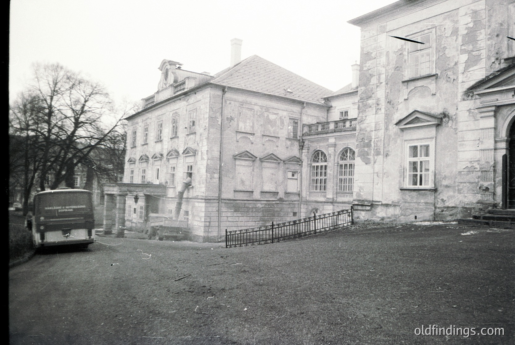 Neoclassical stone building with arched windows and decorative balustrades, likely mid-20th century. Prominent gabled roof and symmetrical façade. Vintage truck parked in foreground, suggesting historical or archival context.
