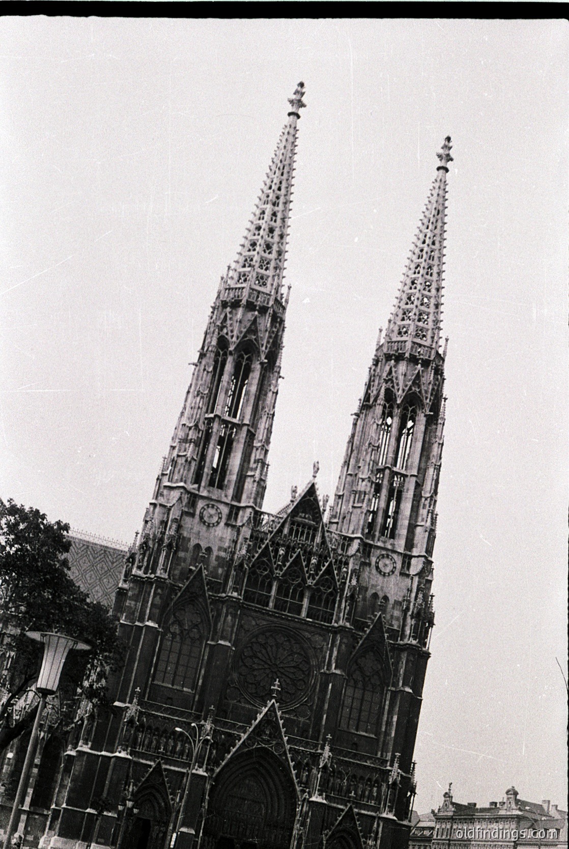 Gothic twin spires with intricate stone tracery and pointed arches dominate this mid-20th century cathedral facade. Ornate rose windows and buttresses frame the grand entrance, reflecting European ecclesiastical architecture. Likely