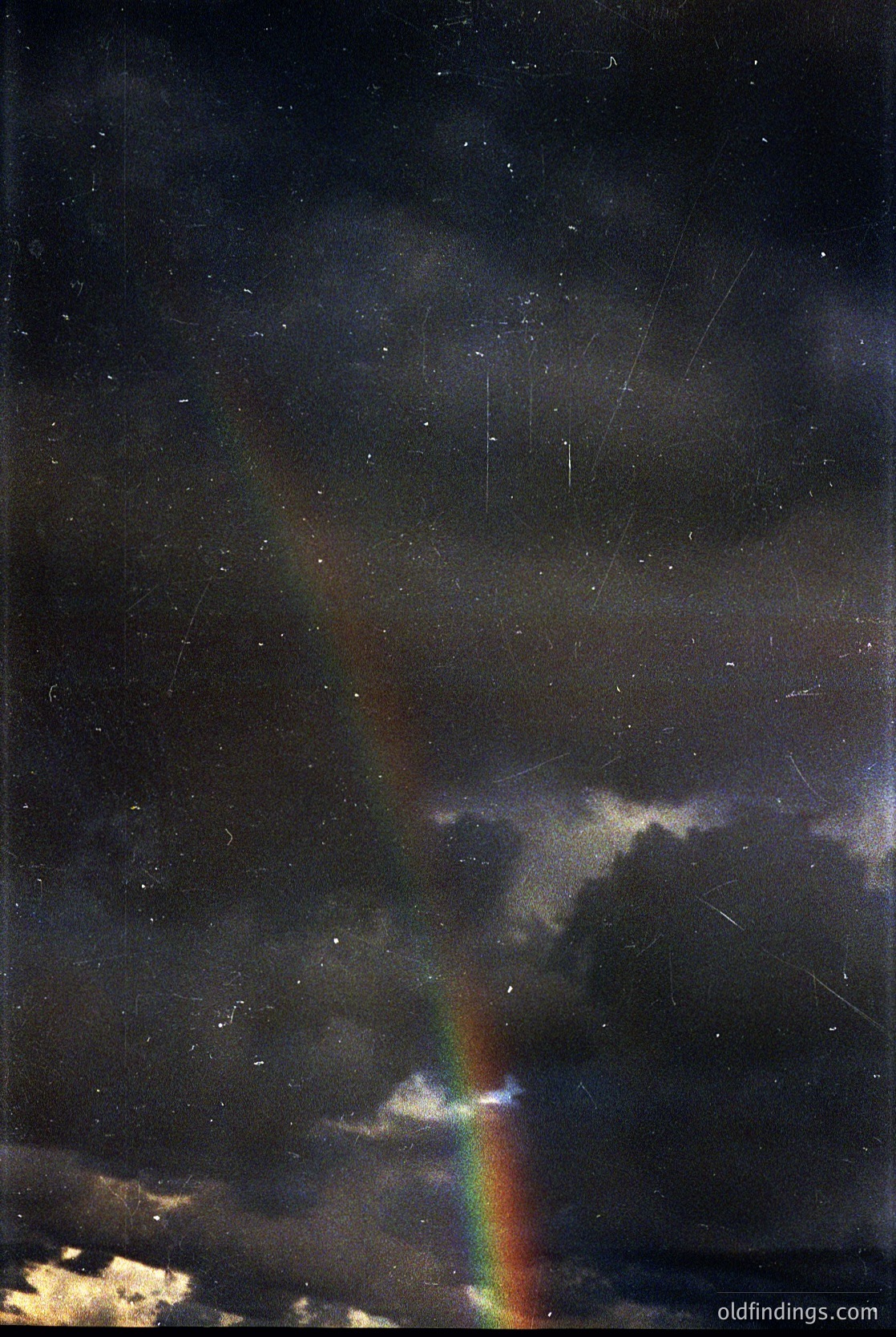Vivid double rainbow piercing storm clouds under dramatic skies. Bold red/orange arc contrasts with softer blue/green. Raindrops suspended mid-air capture light. Timeless natural phenomenon with high contrast for artistic/editorial use.
