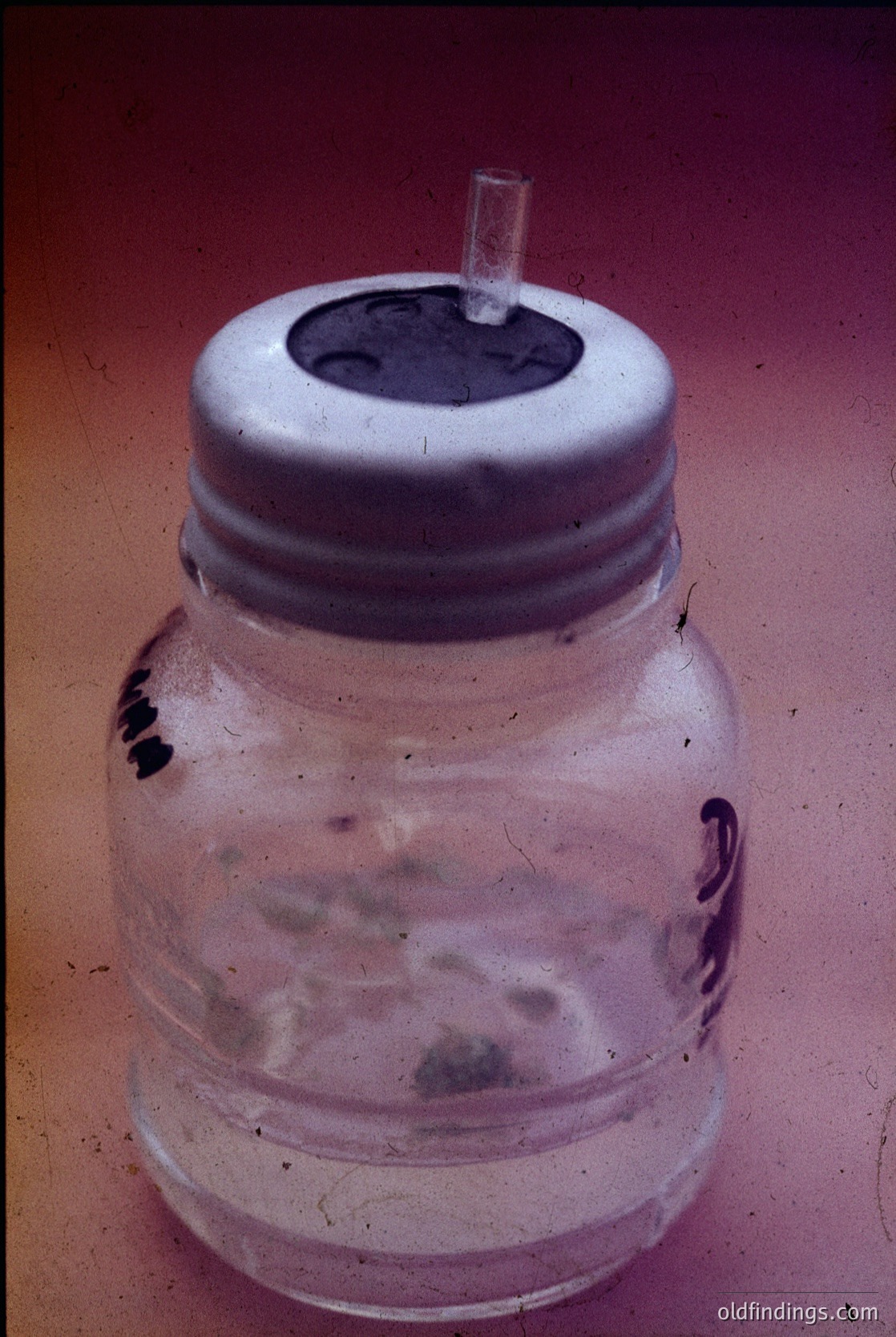 Vintage glass jar with white plastic screw-on lid featuring a small spout, likely for pouring liquids. Surface shows minor wear and residue stains. Mid-20th century industrial or household storage design.