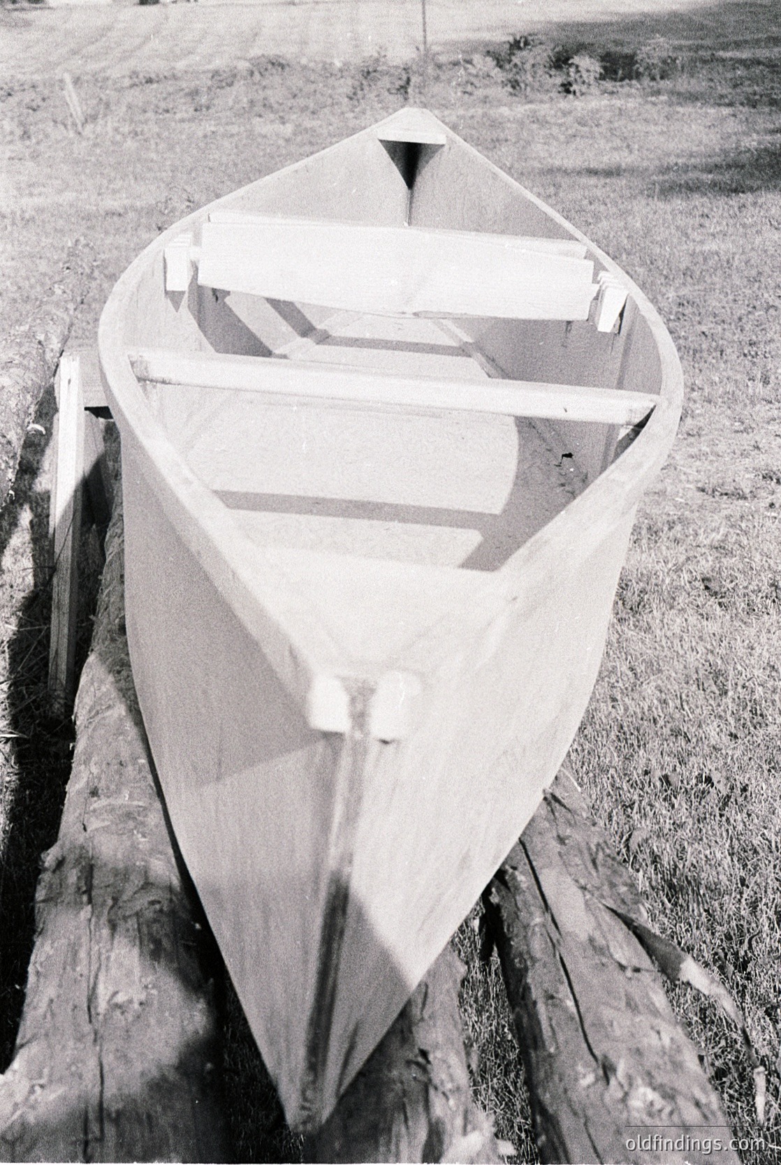 Classic wooden rowboat with pointed bow and simple frame, resting on a dry dock. Constructed from planks and ribs, likely mid-20th century. Ideal for vintage maritime or historical research.