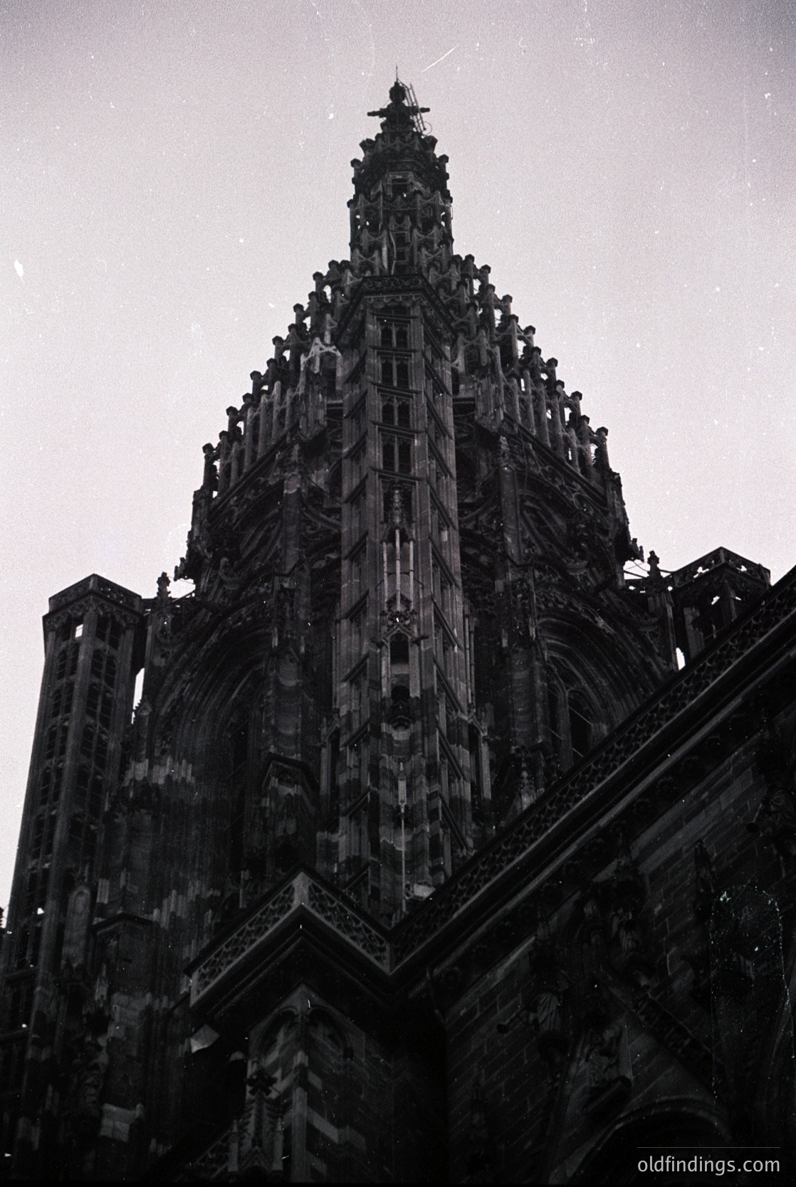 Gothic spire with intricate tracery and pinnacles, likely part of a European cathedral. Stonework features vertical buttresses and pointed arches. Nighttime lighting highlights architectural details.