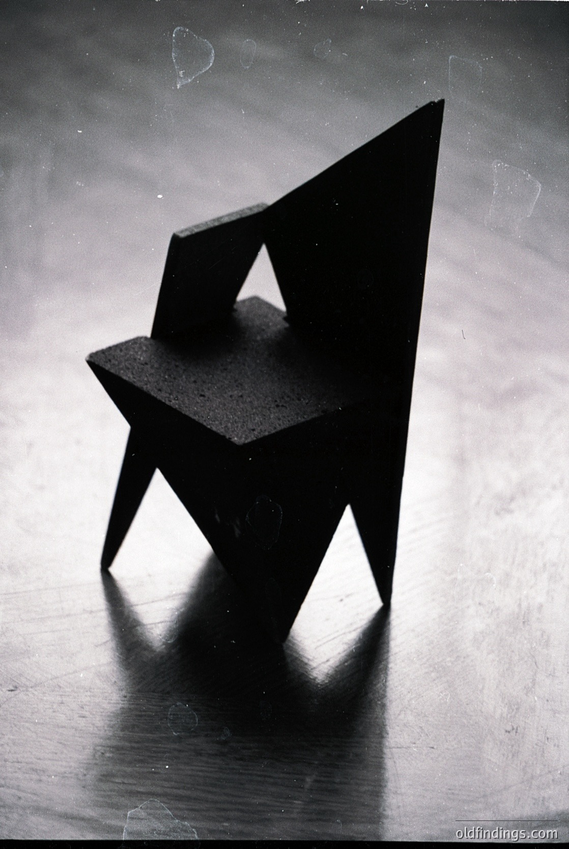 Minimalist geometric chair with angular, floating seat and legs—evoking mid-century modern design. Sharp lines and monochromatic contrast highlight structural simplicity. Ideal for industrial or contemporary interior references.