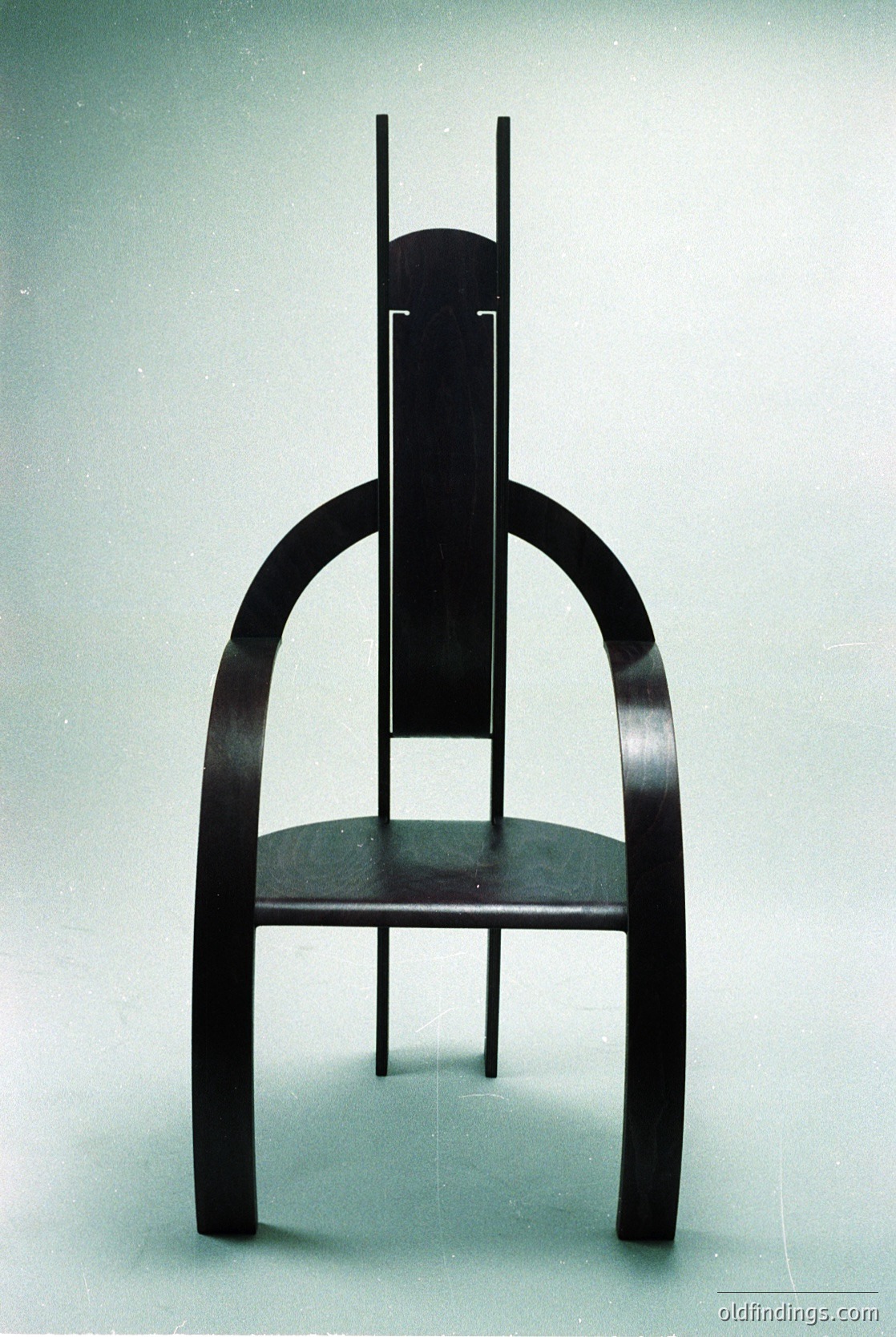 Mid-century modern chair with sculptural wooden legs and curved backrest, likely walnut or teak. Clean lines, minimalist design, and integrated seat frame. Ideal for vintage-inspired interiors or design references.