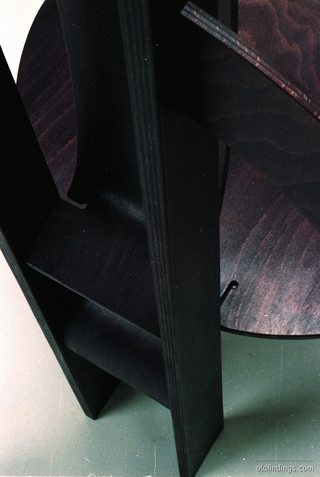 Mid-century modern wooden chair with angular, tapered legs and a curved backrest, showcasing clean lines and minimalist design. Dark-stained wood with smooth, polished finish. Ideal for interior design references or furniture history research.