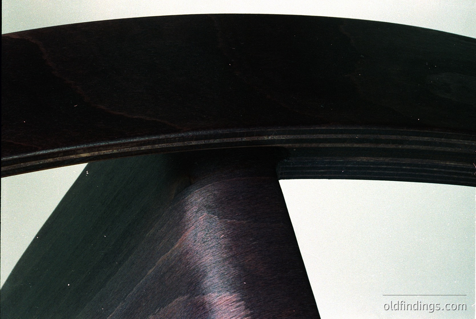 Close-up of a sleek, curved wooden chair leg with smooth, dark finish—likely mid-century modern design. The polished grain and tapered shape suggest functional minimalism. Ideal for interior design references or furniture history research.