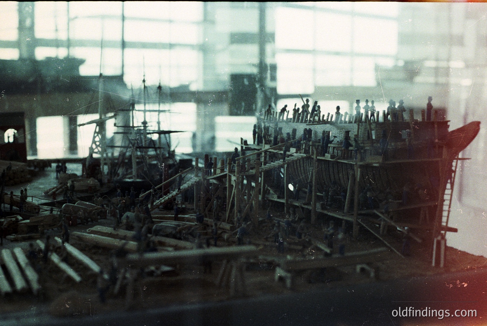 Detailed 19th-century wooden ship model showcasing intricate rigging, multiple masts, and lifelike crew figures. Exhibited indoors under glass, likely in a maritime museum or historical collection.