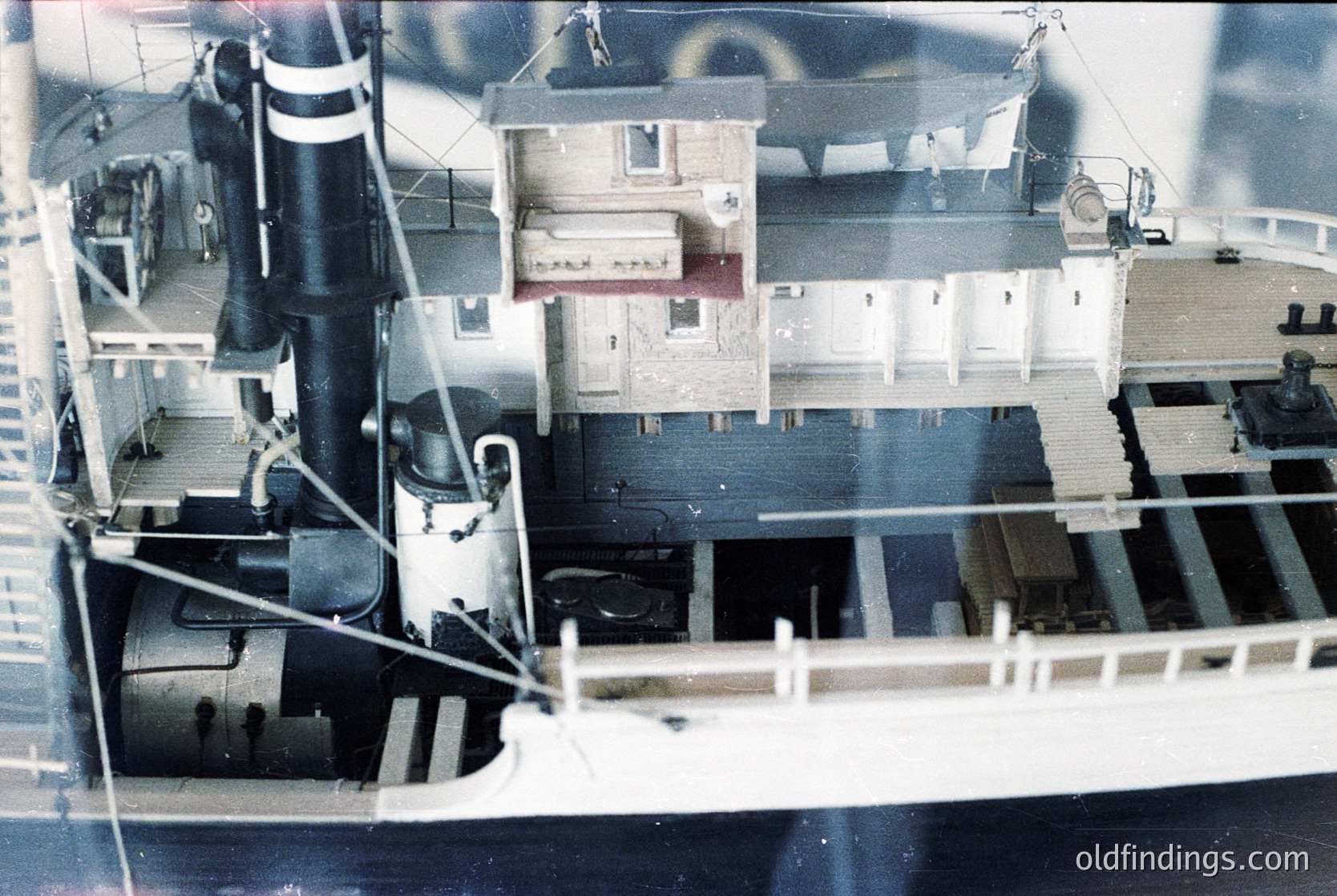 Miniature model of a mid-20th century industrial ship, featuring a smokestack, lifeboat, and deck machinery. The structure includes a small cabin with a pitched roof. Likely used for maritime education or display.