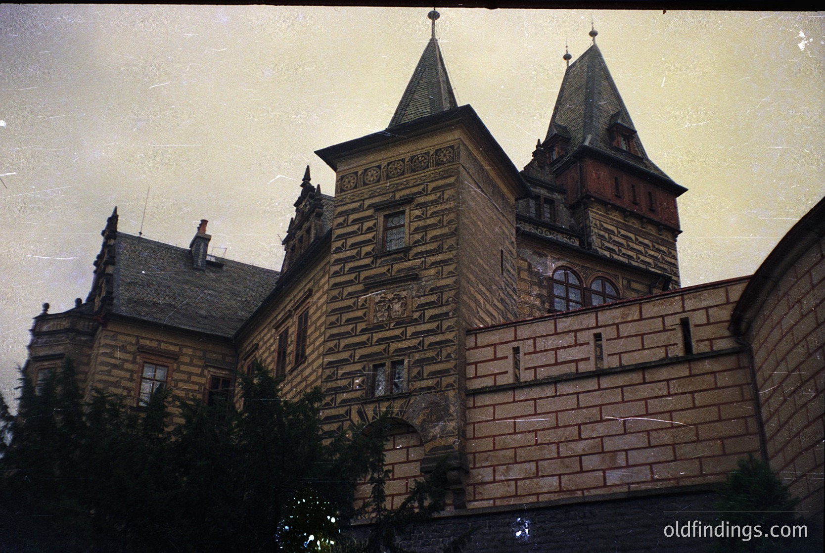 Historic stone building with twin spires and intricate brickwork, likely European . Symmetrical facade features arched windows and decorative stone carvings. Vintage sepia tone suggests mid-20th century photography (). Potential institutional or public use (, ).