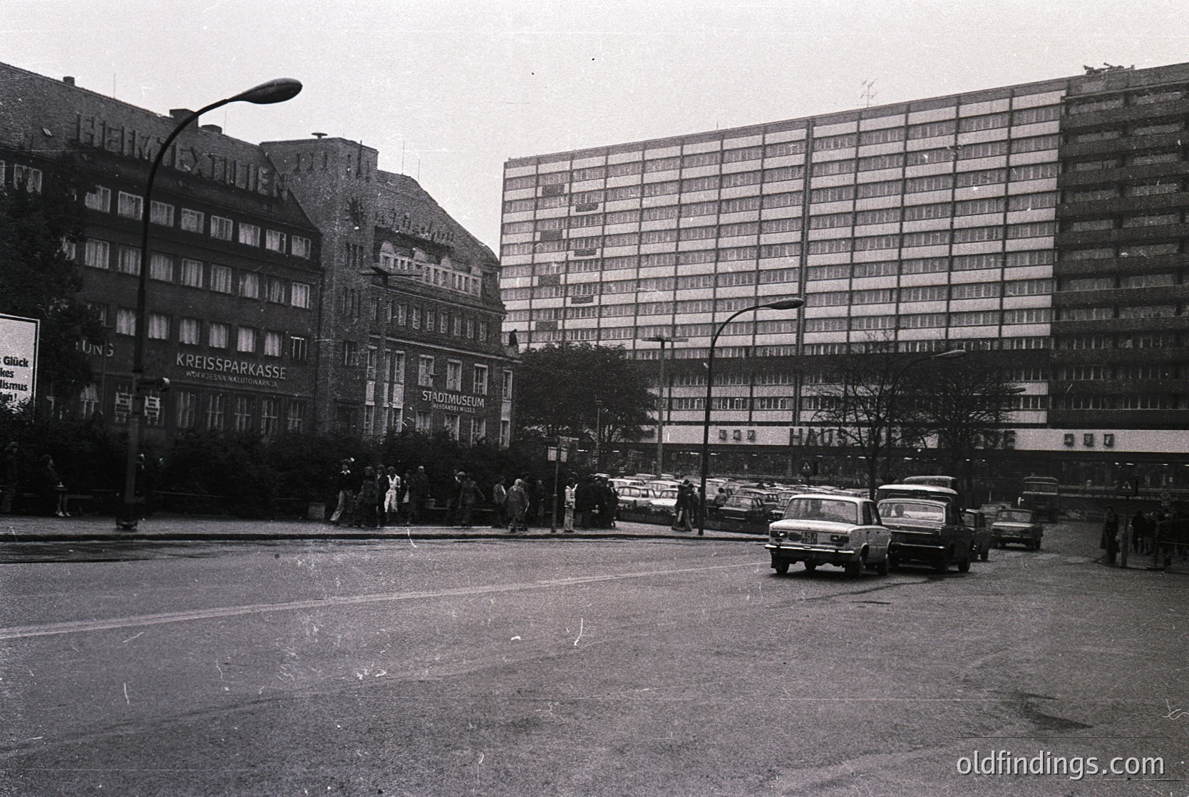 Mid-20th century urban scene featuring **Kreissparkasse** (regional savings bank) building with classic German signage. Crowded street with vintage cars, pedestrians, and early Brutalist-style apartment blocks. Likely **West Germany**, 1960s–1970s.